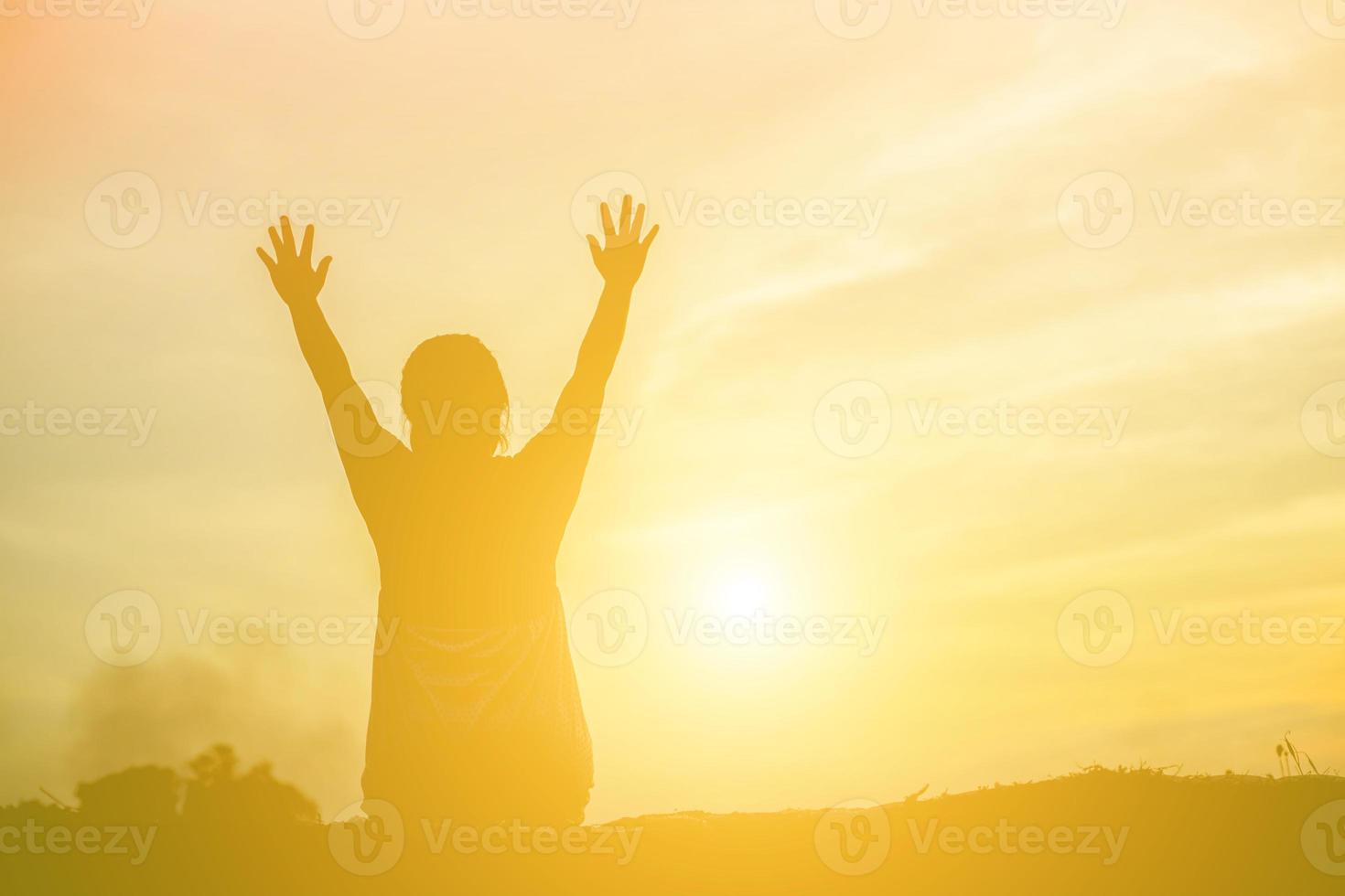 Silhouette einer Frau, die über einem schönen Himmelshintergrund betet foto
