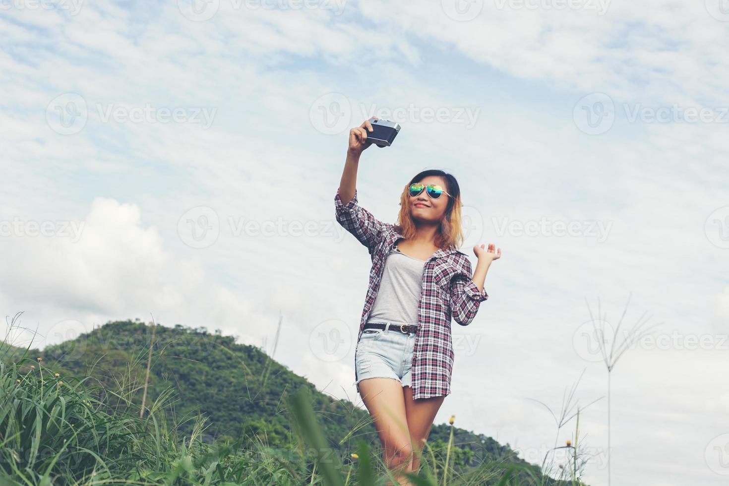 junge Hipster-Frau mit Retro-Kamera, die Landschaft im Freien, Lifestyle-Gebirgsnatur im Hintergrund erschossen hat. foto