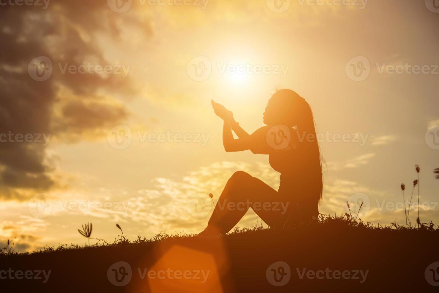 Silhouette einer Frau, die über einem schönen Himmelshintergrund betet foto