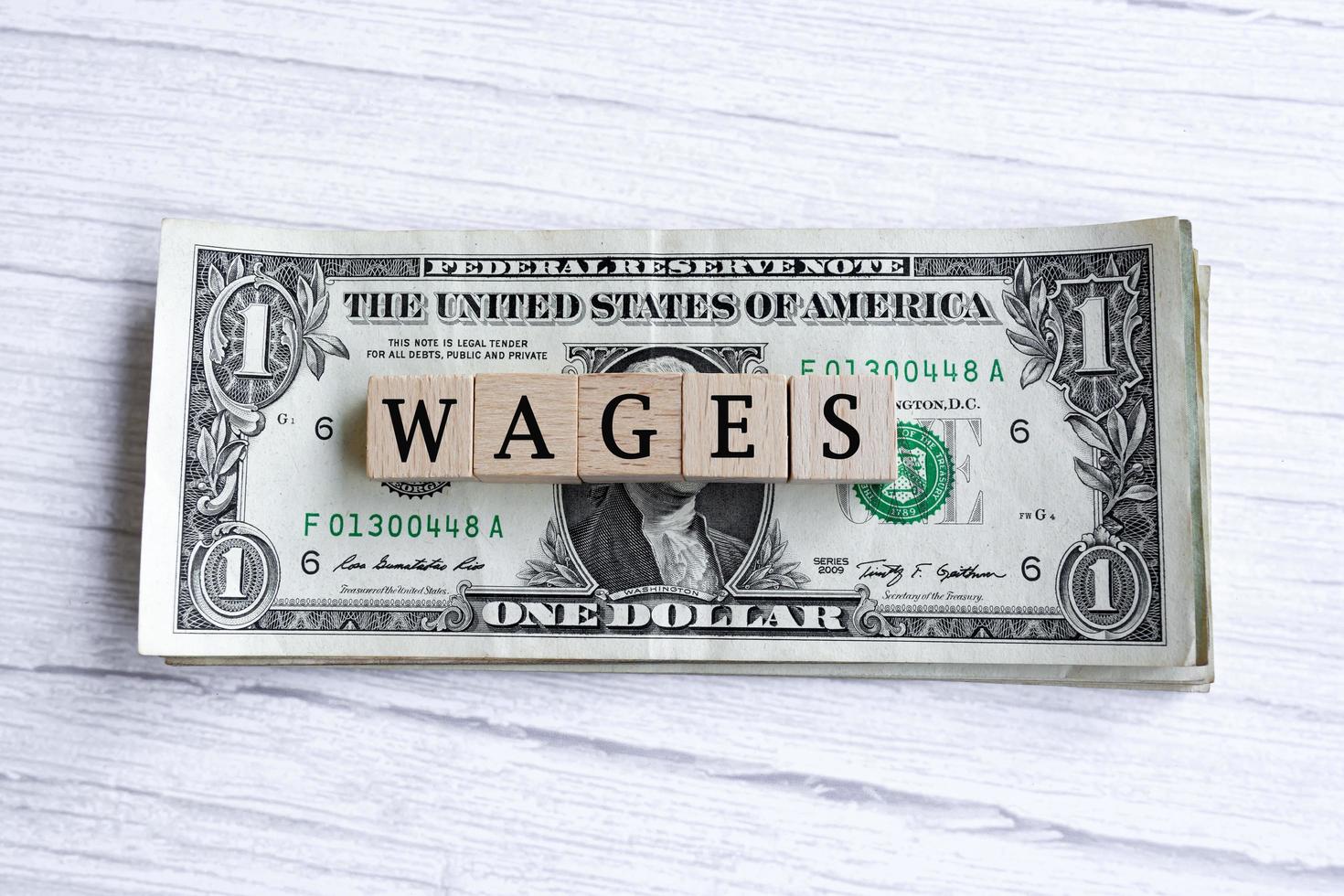 Löhne Wort auf Holzblock mit amerikanischen Dollarnoten geschrieben. direkt darüber. foto
