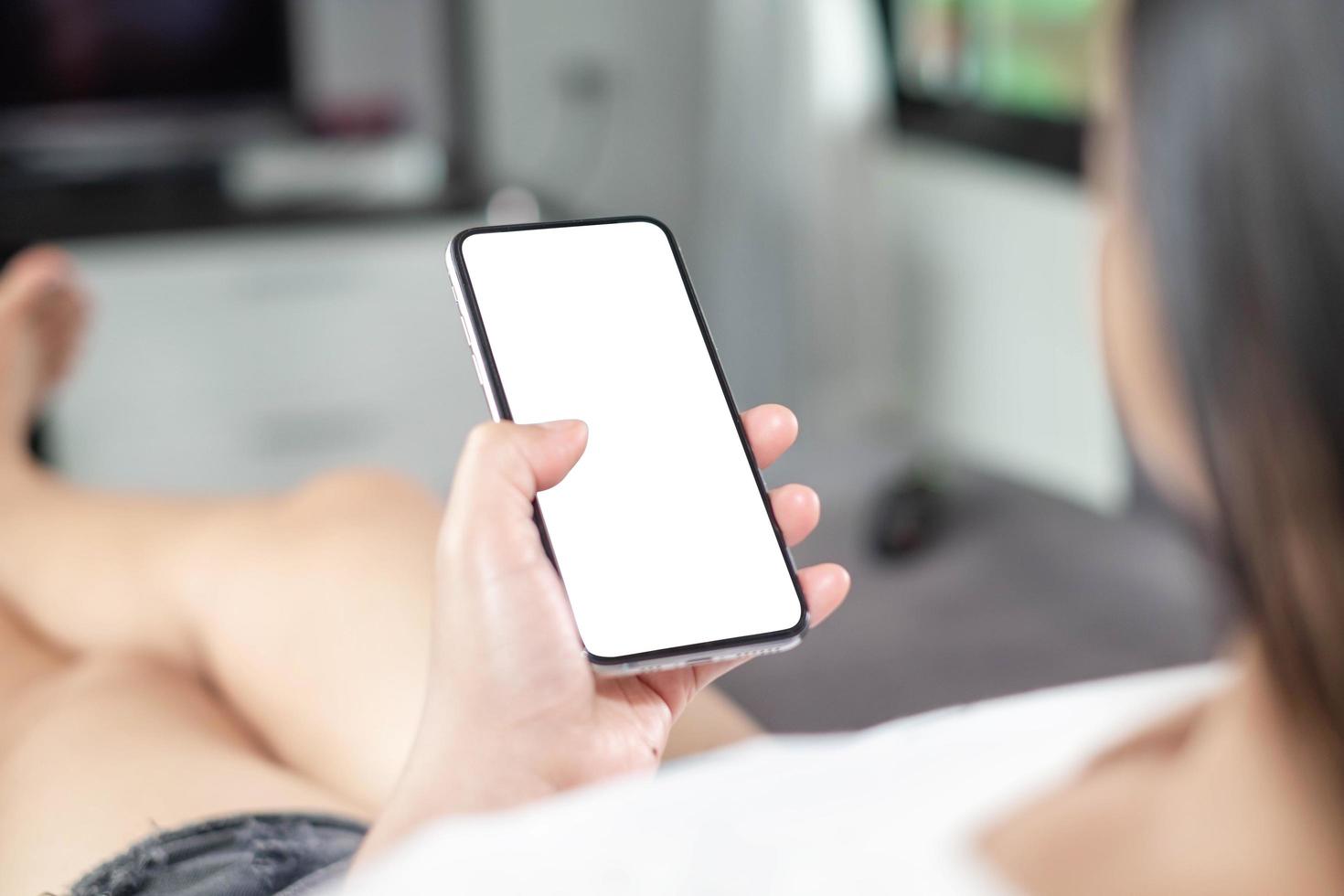 Mockup-Telefon in der Hand der Frau mit weißem Bildschirm zu Hause, aufgenommen aus der Rückansicht, minimales Konzept foto