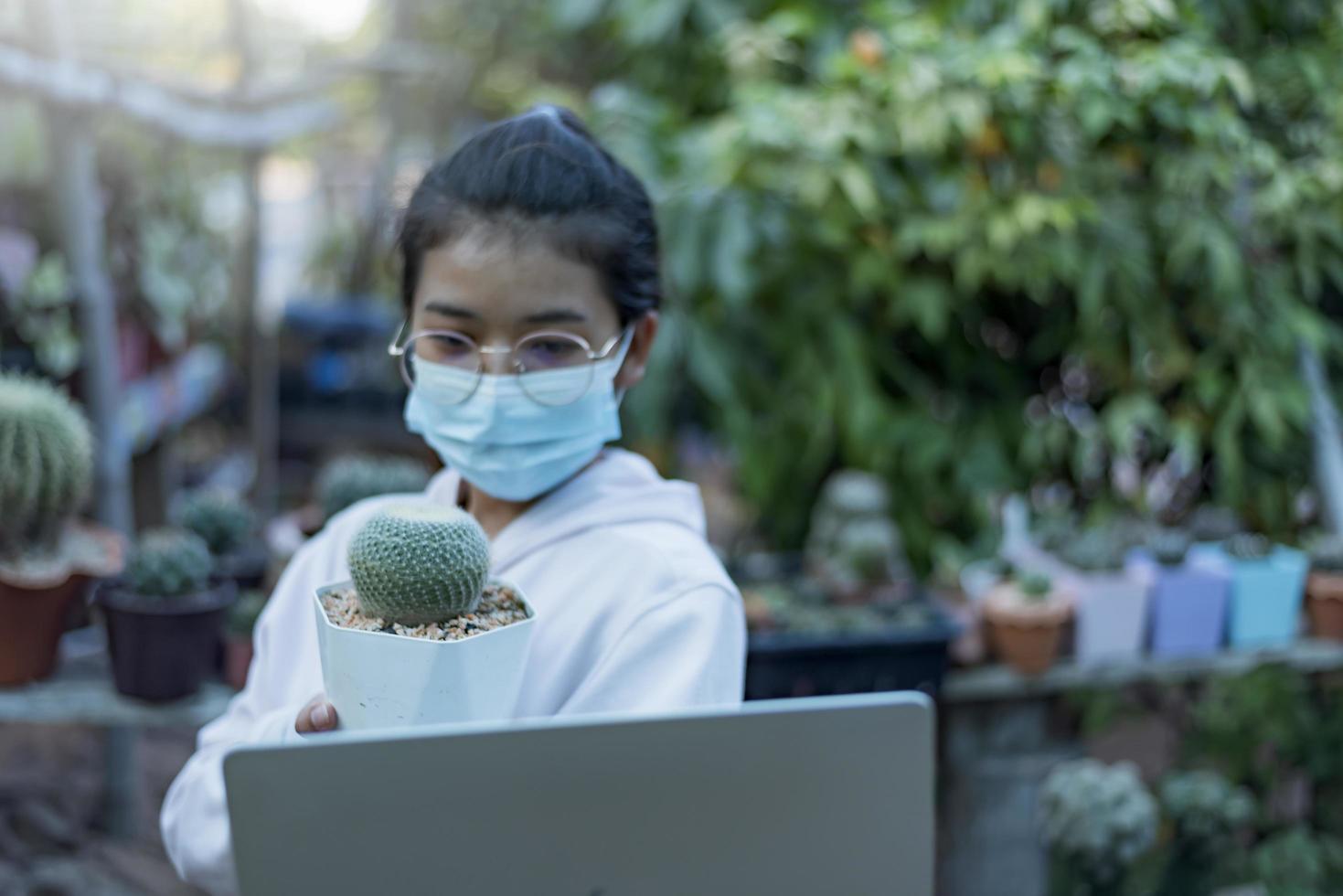 schöne asiatische Gewächshausarbeiterin, die kleine Pflanzen im Live-Stream der sozialen Medien mit dem Handy verkauft. Gärtner für kleine Baumlandschaften und Hausgartendekorationen. foto