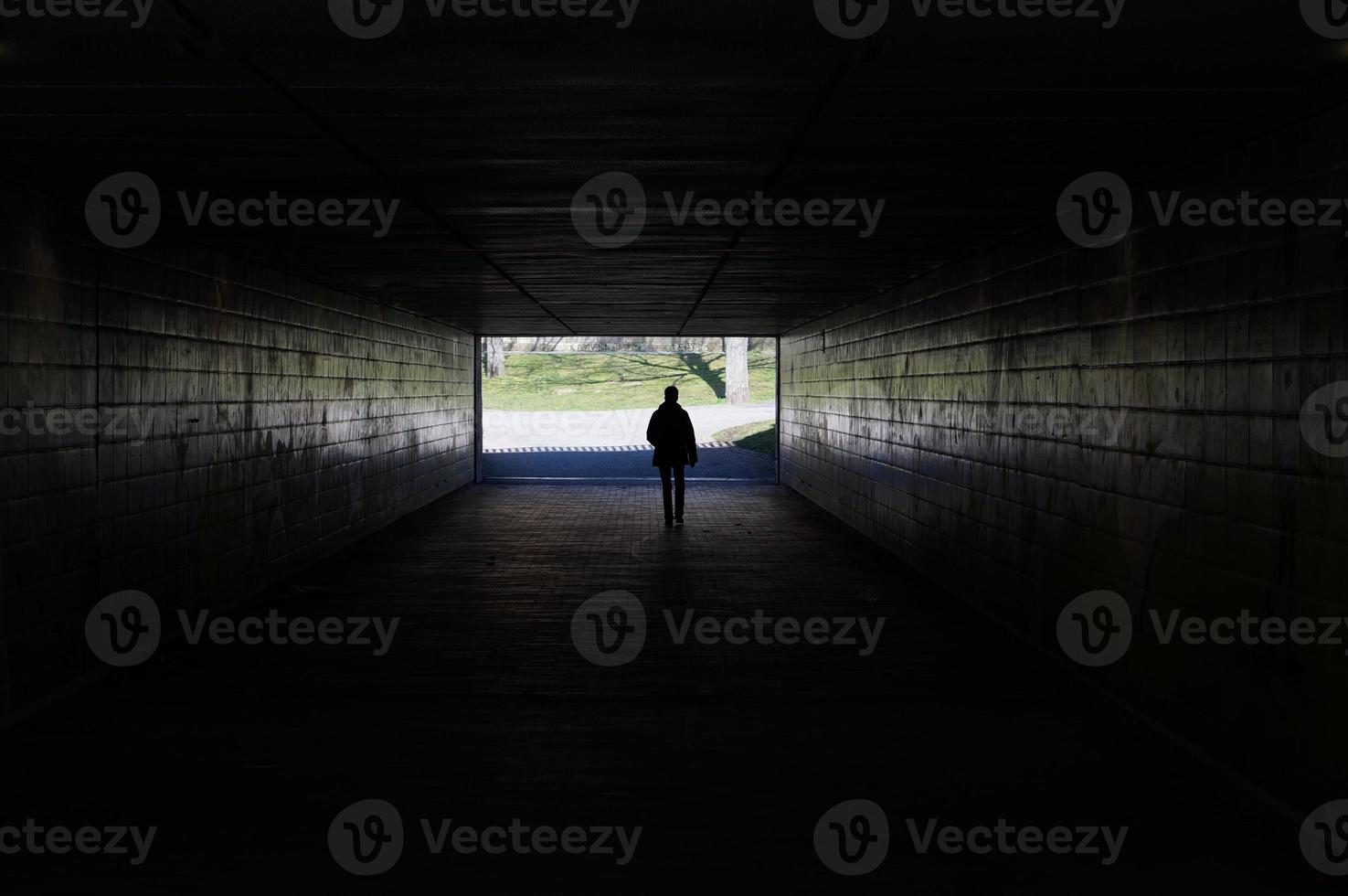 fußgänger, der durch dunklen tunnel geht foto