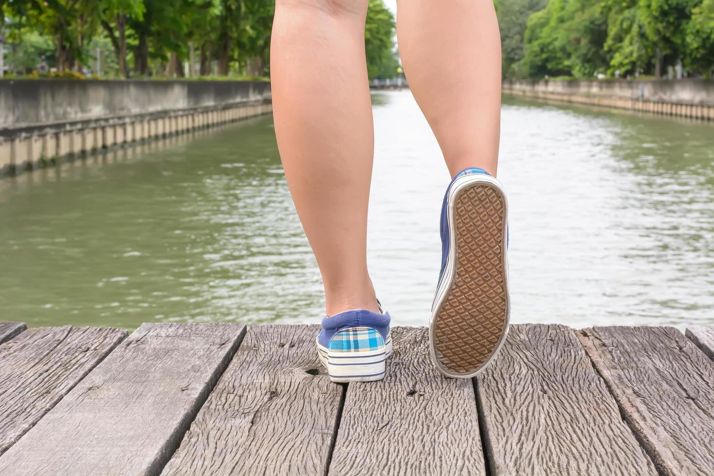 Segeltuchturnschuhe an den Füßen auf der Holzbrücke foto