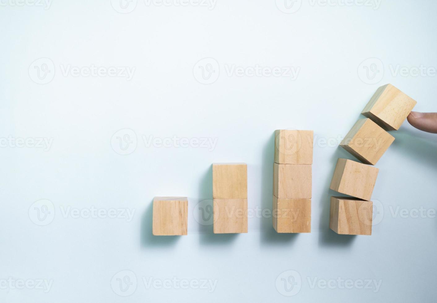 Draufsicht Finger drücken Holzklötze vor dem Zusammenbruch. Konzept zum Schutz von Unternehmen. foto