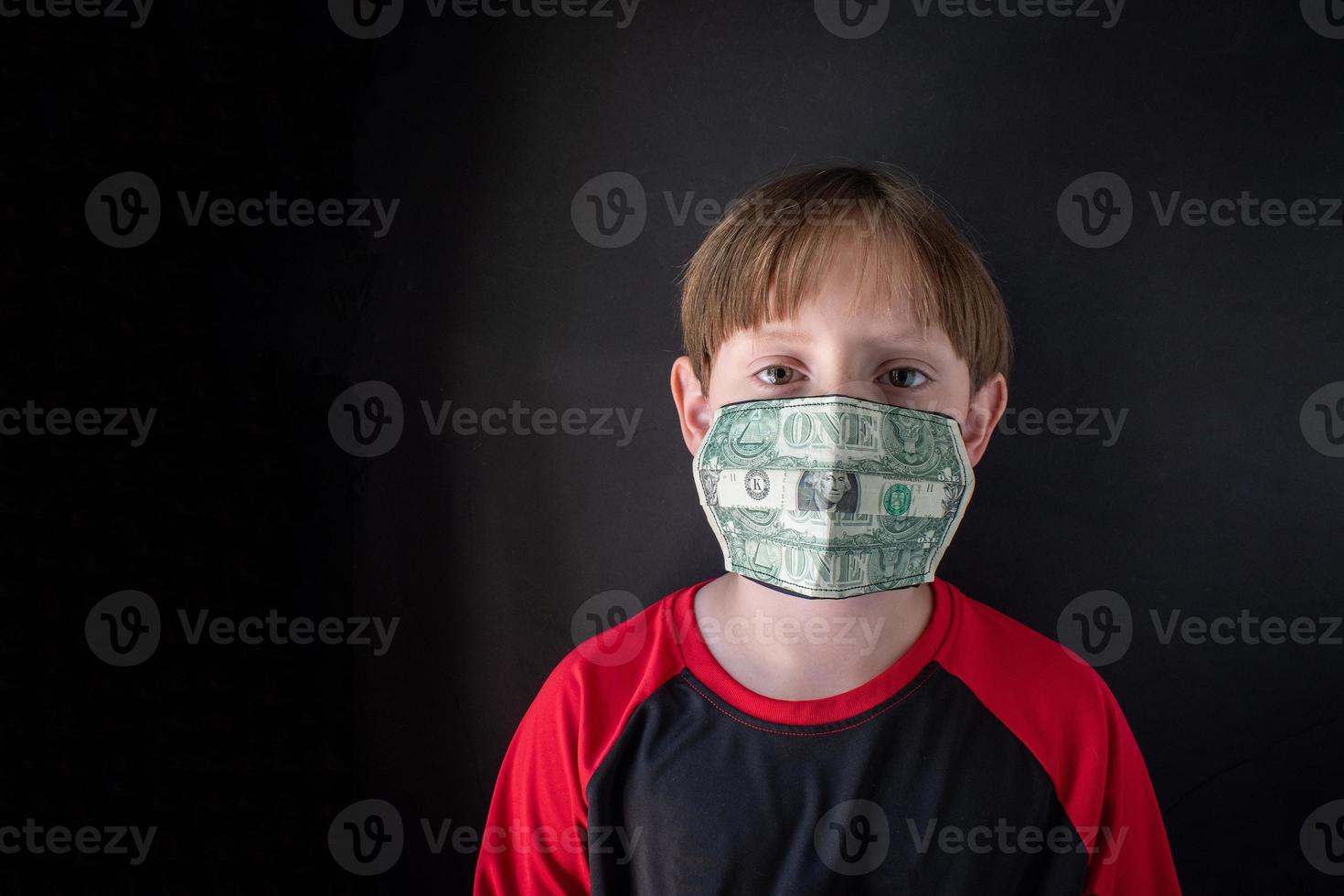 die tatsächlichen Kosten einer Pandemie mit medizinischer Maske aus Geld im Gesicht des Kindes foto