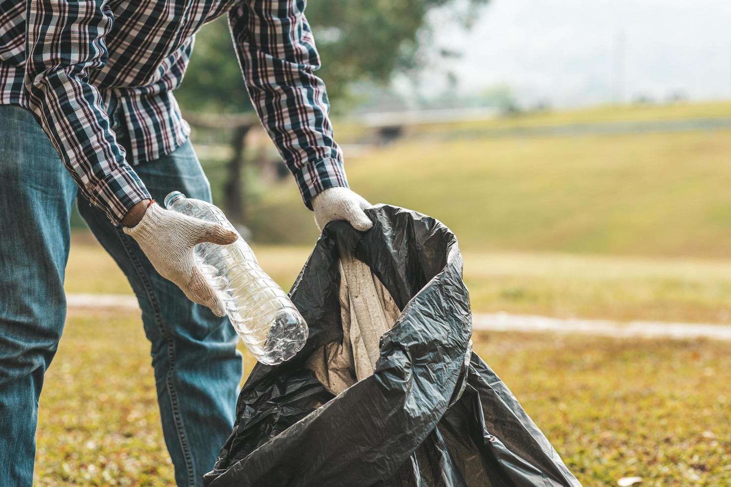 Ein Mann sammelt Müll in einem Park auf, wenn er keinen Müll in den Müll wirft, kann dies die Schönheit des Gartenbereichs ruinieren und auch die globale Erwärmung verursachen und Tieren schaden. Konzept der Sauberkeit in öffentlichen Bereichen. foto