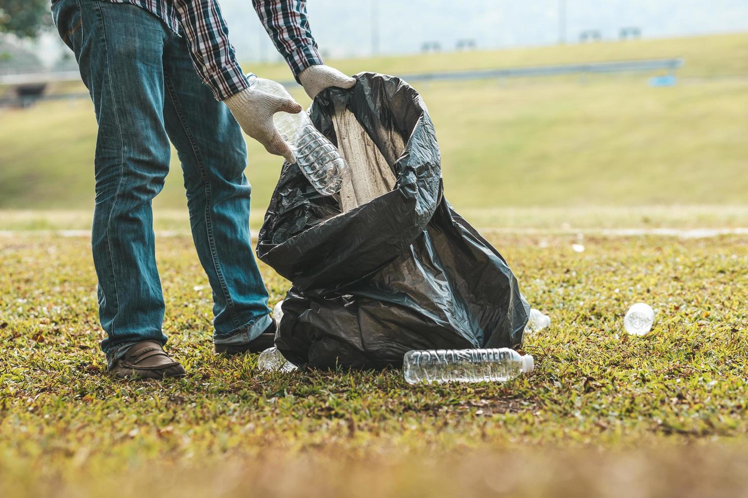 Ein Mann sammelt Müll in einem Park auf, wenn er keinen Müll in den Müll wirft, kann dies die Schönheit des Gartenbereichs ruinieren und auch die globale Erwärmung verursachen und Tieren schaden. Konzept der Sauberkeit in öffentlichen Bereichen. foto