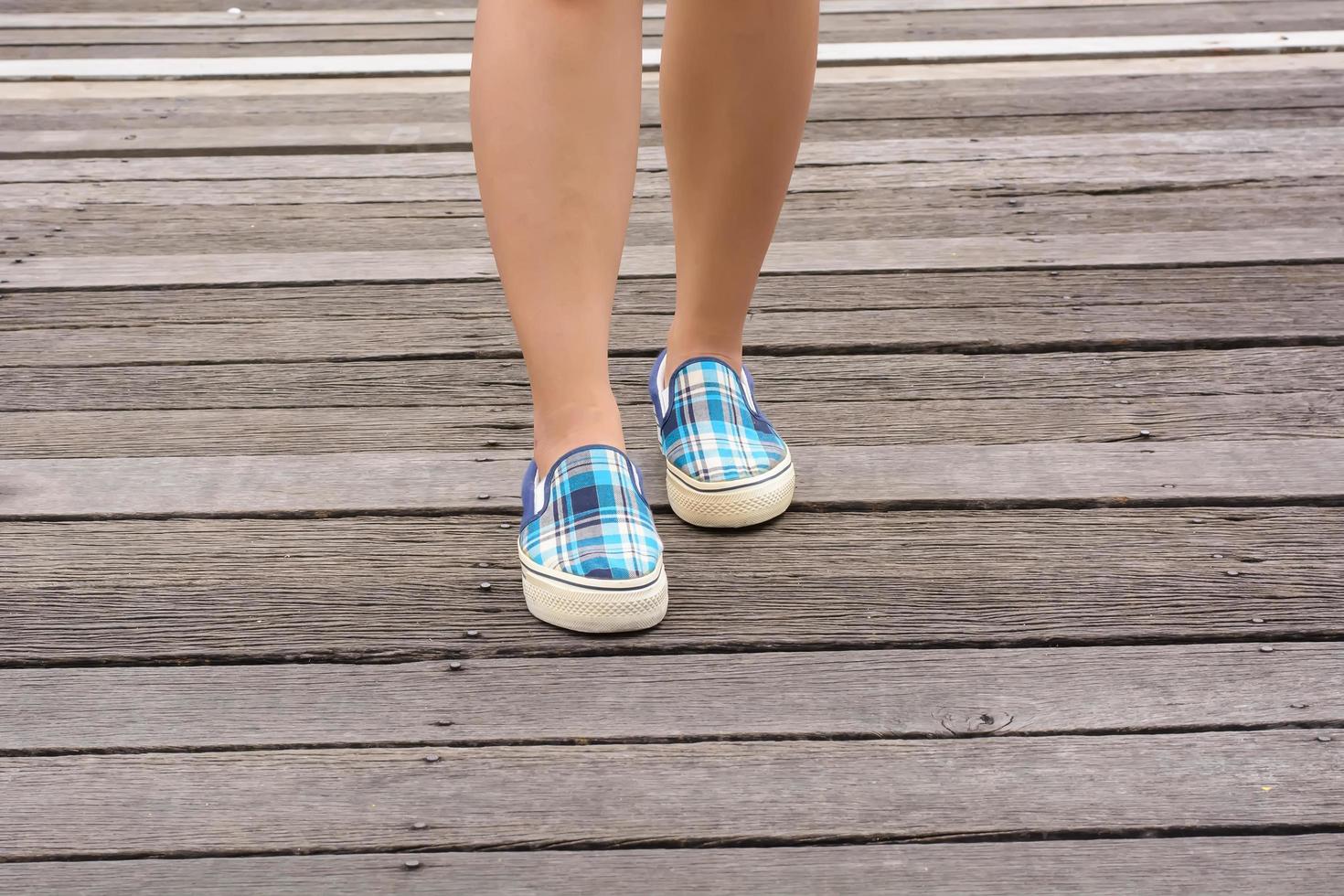 Segeltuchturnschuhe an den Füßen auf der Holzbrücke foto