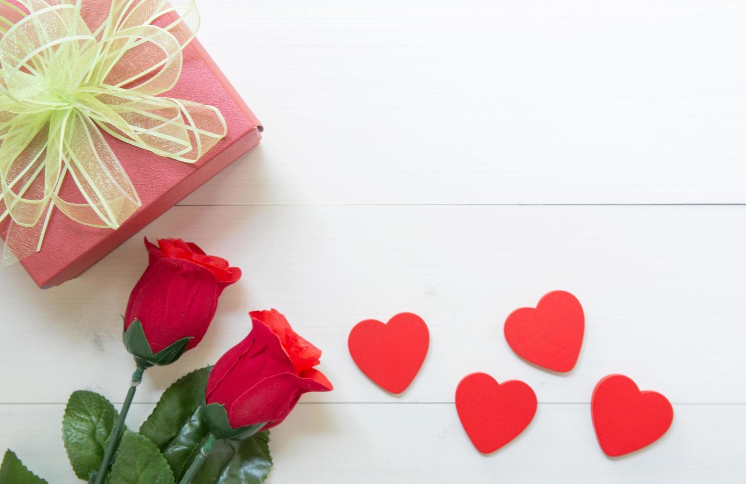 Präsentgeschenk mit roter Rosenblume und Geschenkbox mit Schleifenband und Herzform auf Holztisch, 14. Februar des Liebestages mit romantischem, valentinischem Urlaubskonzept, Draufsicht. foto