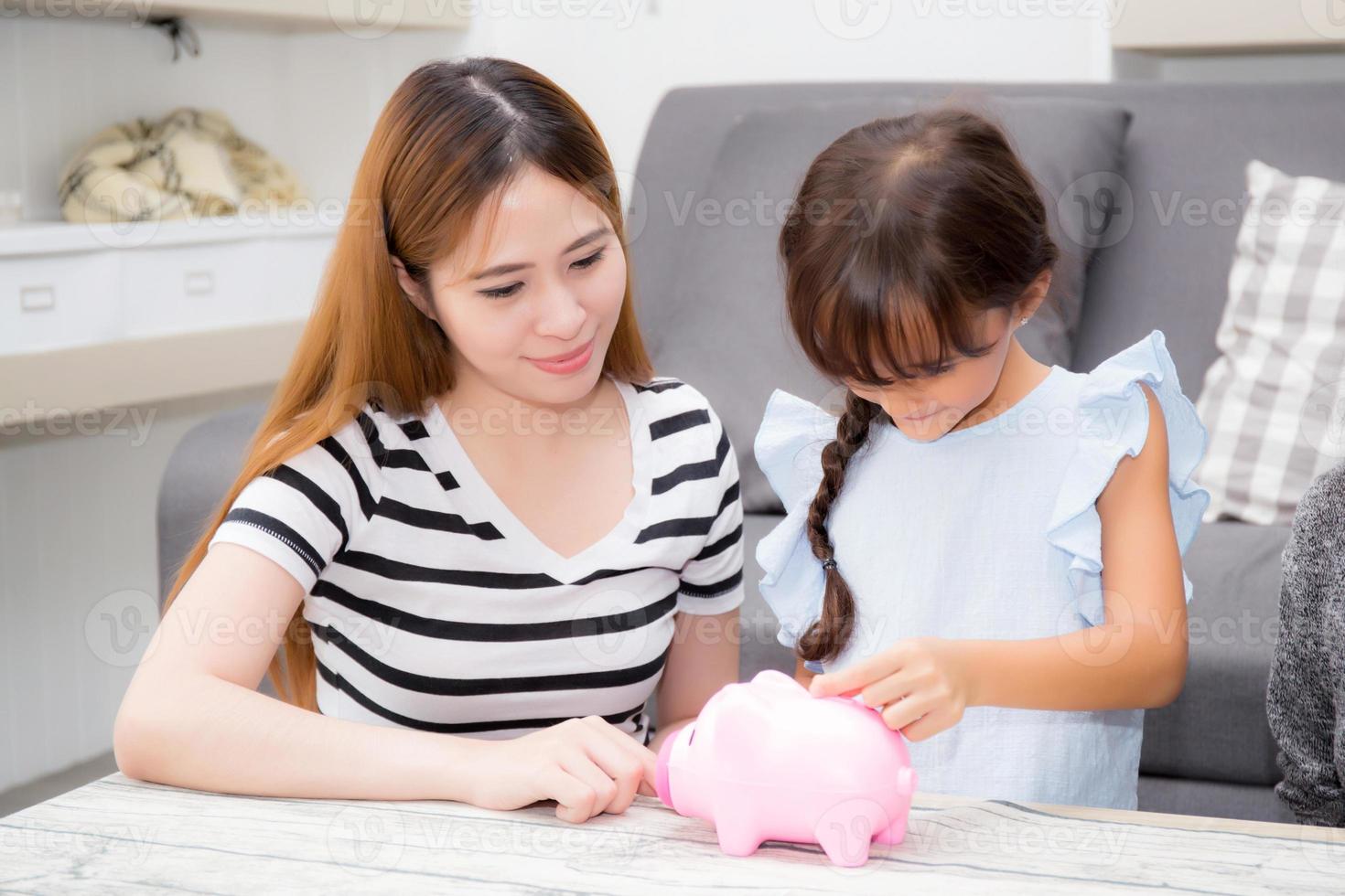 asiatische mutter und tochter legen münze in sparschwein, mutter und kind mit einzahlungskontofamilie, die zusammen geld für die zukunft sparen, finanzkontokonzept. foto