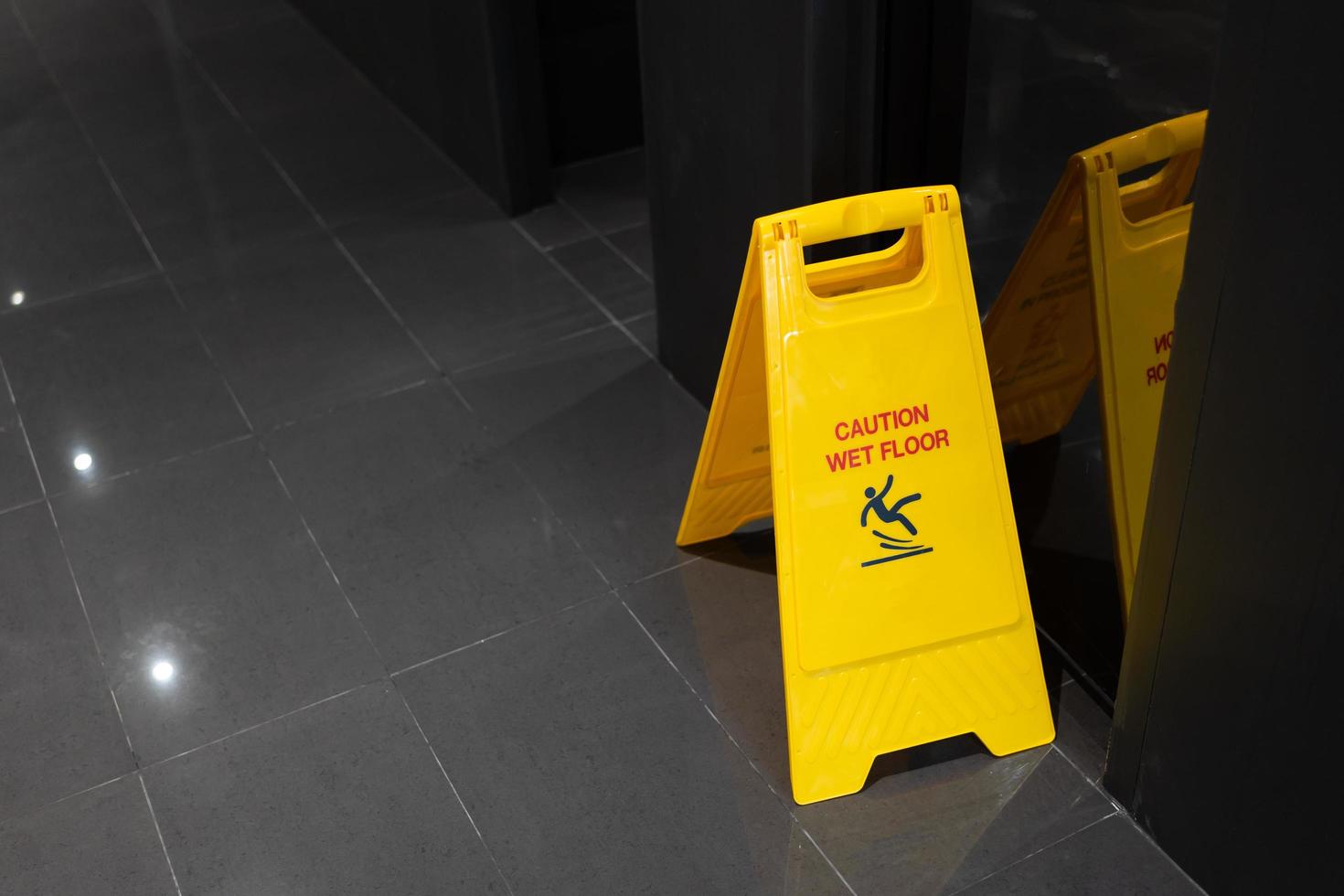 gelbes Vorsichtsschild für rutschigen, nassen Boden auf dem nassen Boden foto
