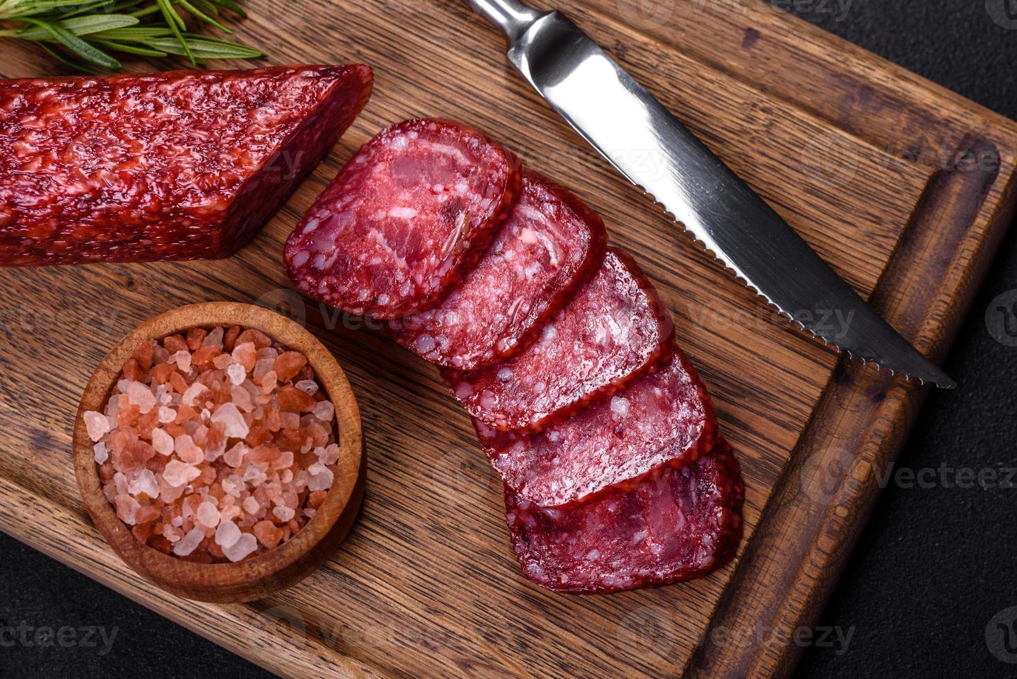 geräucherte Salami mit Rosmarin, Knoblauch und Tomaten auf Holzbrett foto