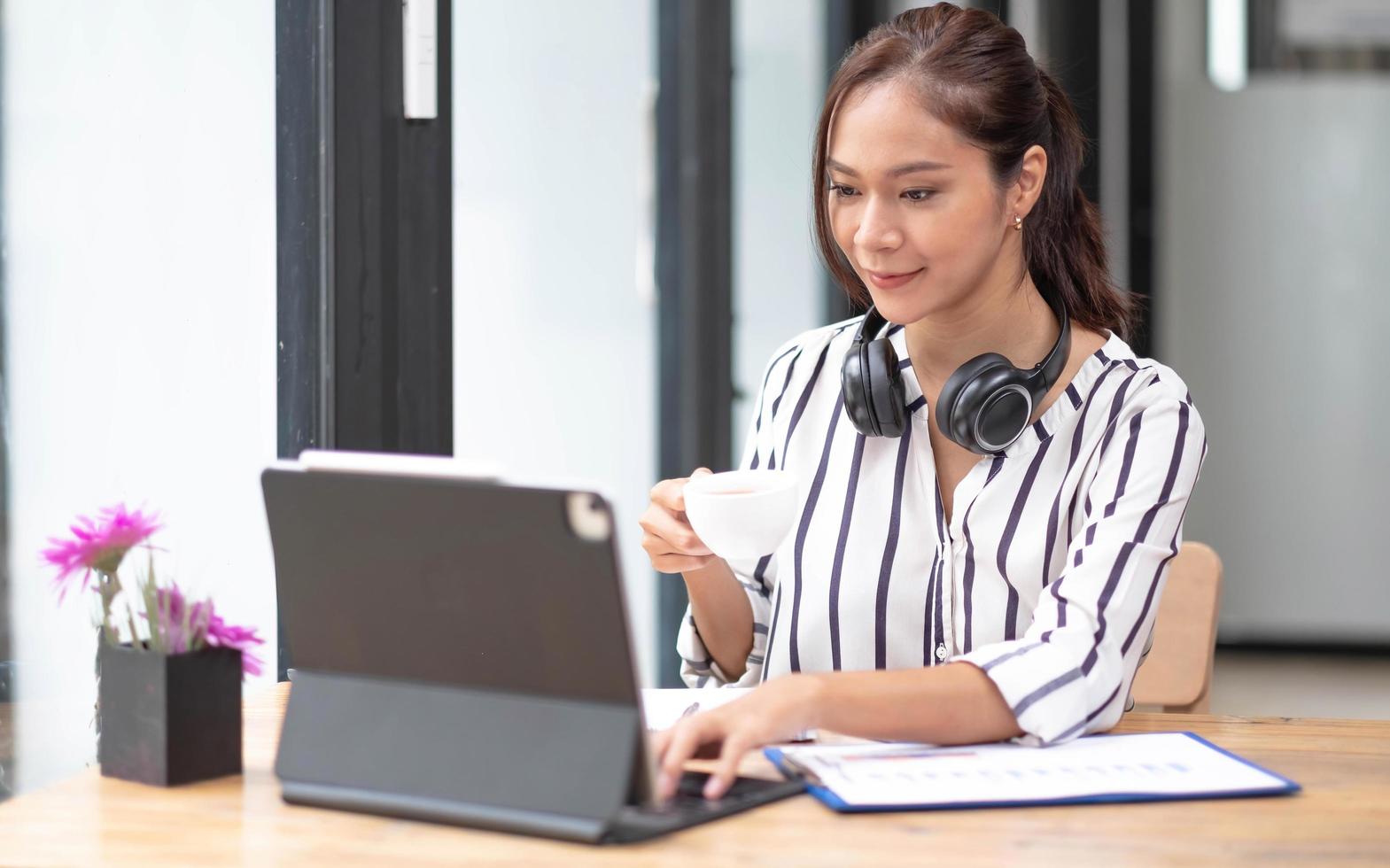 glückliche asiatische frau, die ein headset trägt und mit dem kunden per videocomputeranruf kommuniziert. foto