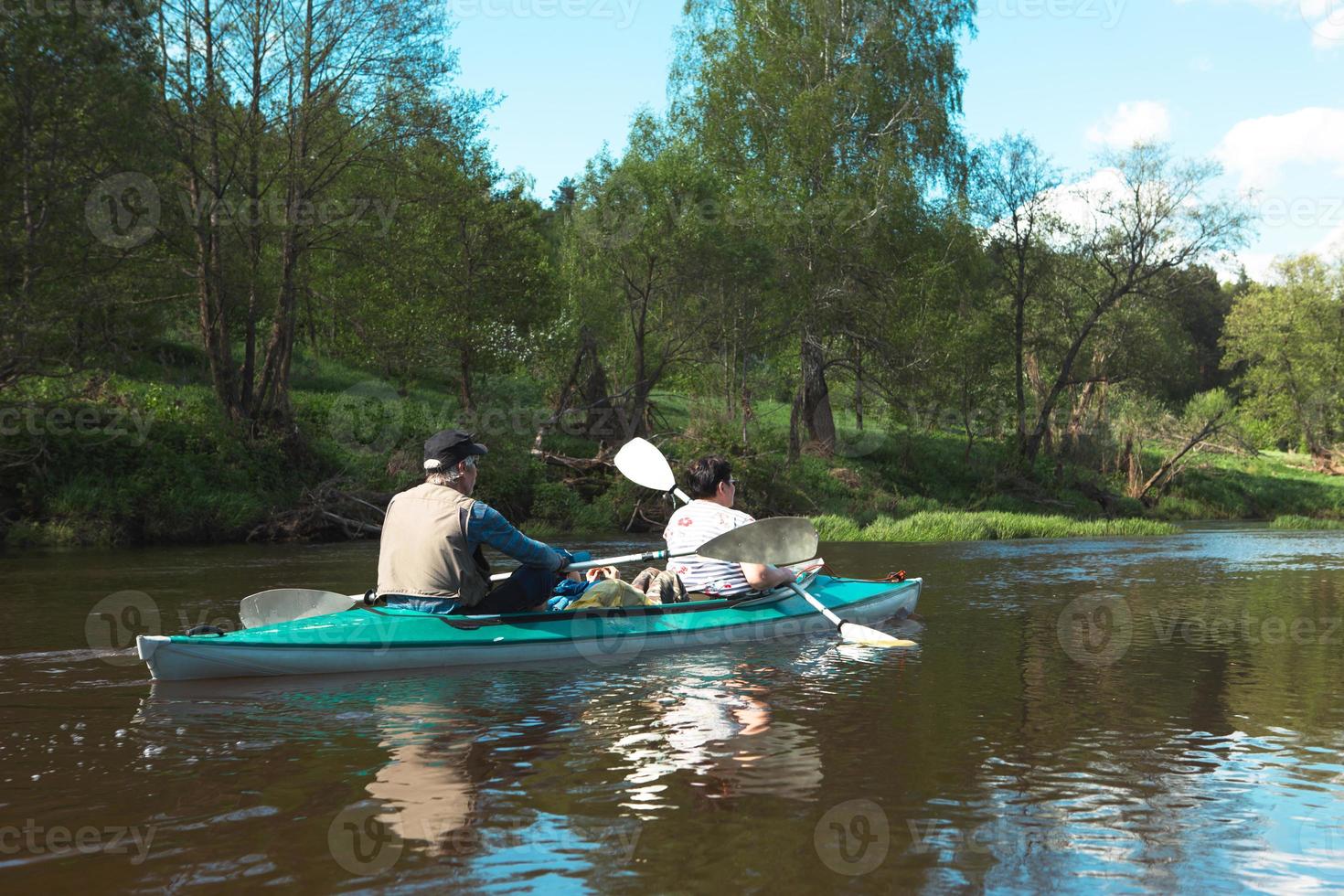 Kajaktour für die Familie. ein älteres Ehepaar, das ein Boot auf dem Fluss rudert, eine Wasserwanderung, ein Sommerabenteuer. Alterssport, geistige Jugend und Gesundheit, Tourismus, aktives Alter foto