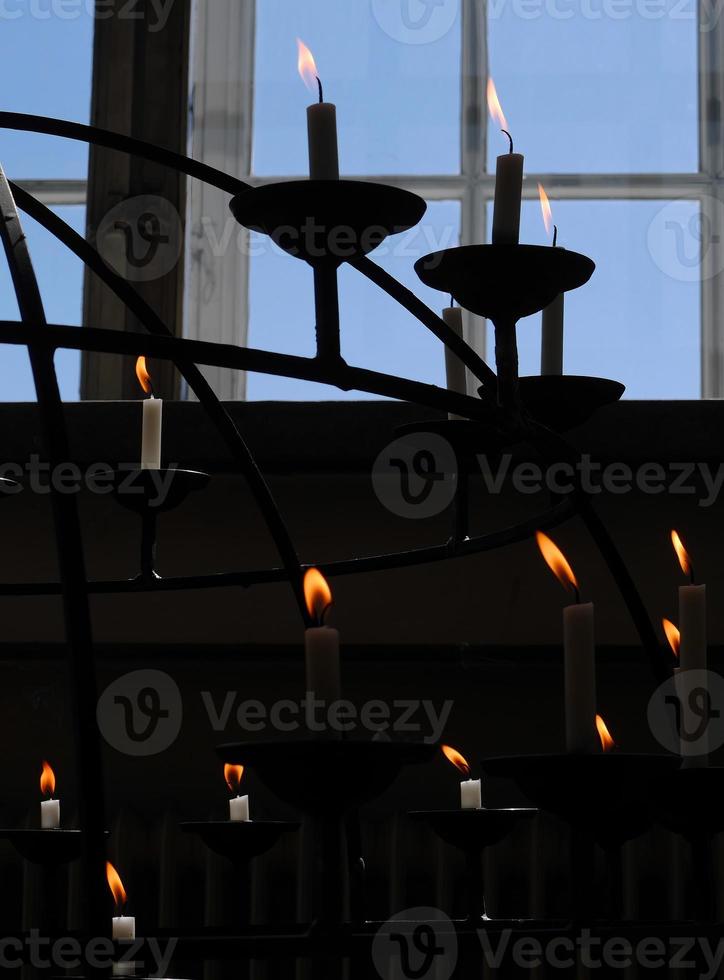 Kontrast von hellen und dunklen Kerzenlichtern auf Kerzenständer in der Kirche mit blauem Himmelshintergrund foto