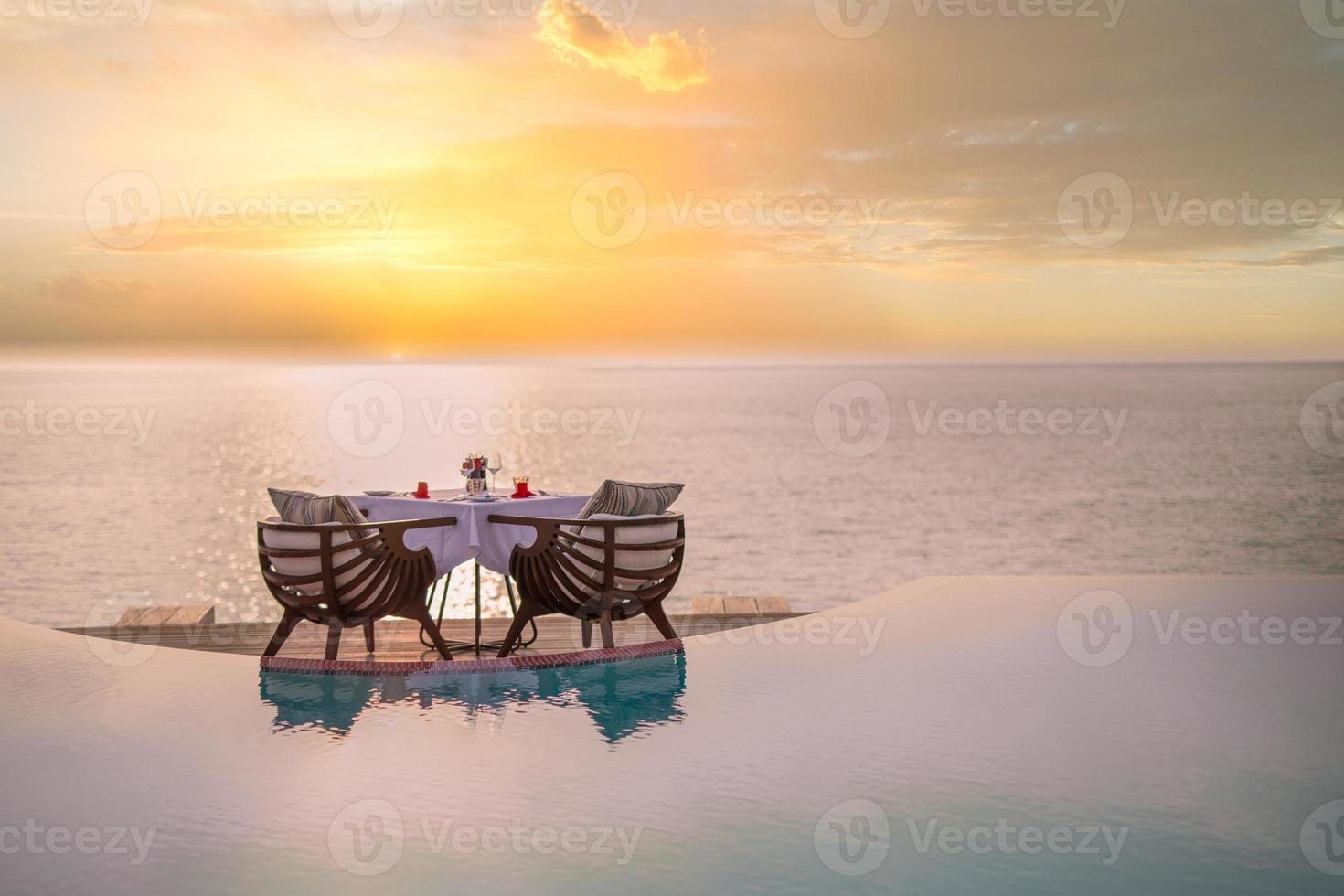 Erstaunliches romantisches Abendessen am Strand auf einer Holzterrasse mit Kerzen unter Sonnenuntergang. Romantik und Liebe, Luxus-Dinner, exotische Tischdekoration mit Meerblick foto