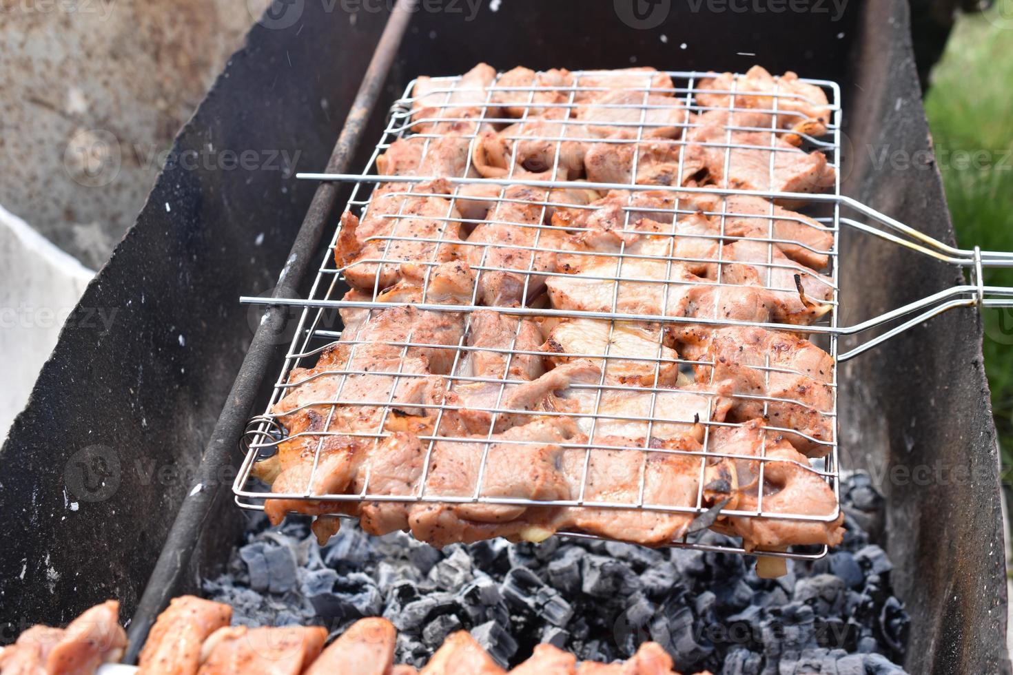 gegrilltes Schweinefleisch in einem Grillnetz mit Gewürzen foto