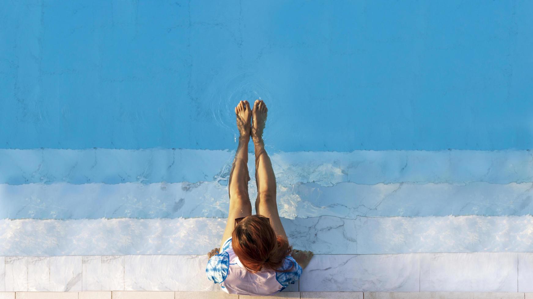 Blick von oben auf die Touristin, die die Entspannung am erfrischenden, blauen, kristallklaren Swimmingpool im Sommerurlaub im luxuriösen tropischen Resort mit Kopierraum genießt foto