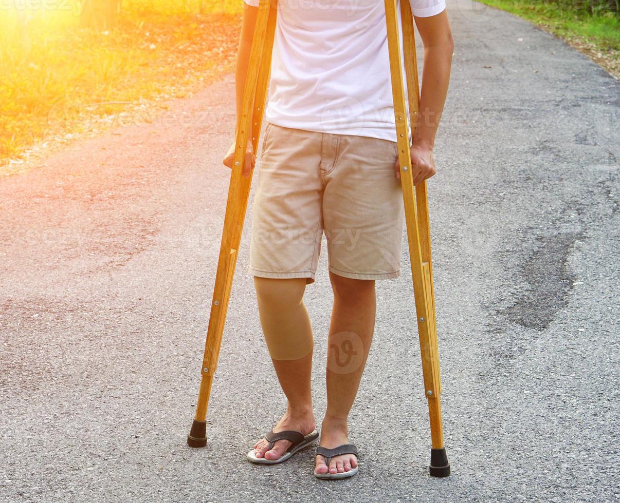 das bild zeigt patienten mit knöchelverletzungen mit bandagen, knöchelorthesen und mit krücken, um das gehen auf dem rasen zu unterstützen. gesundheitswesen und medizinisches konzept. foto