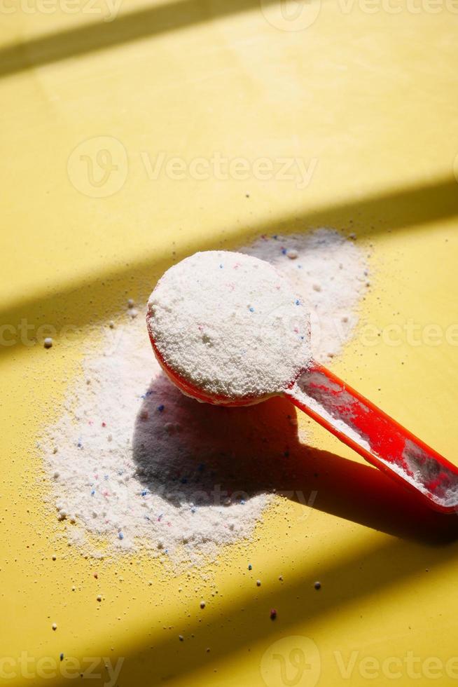 Waschpulver in Plastiklöffel auf blauem Hintergrund foto