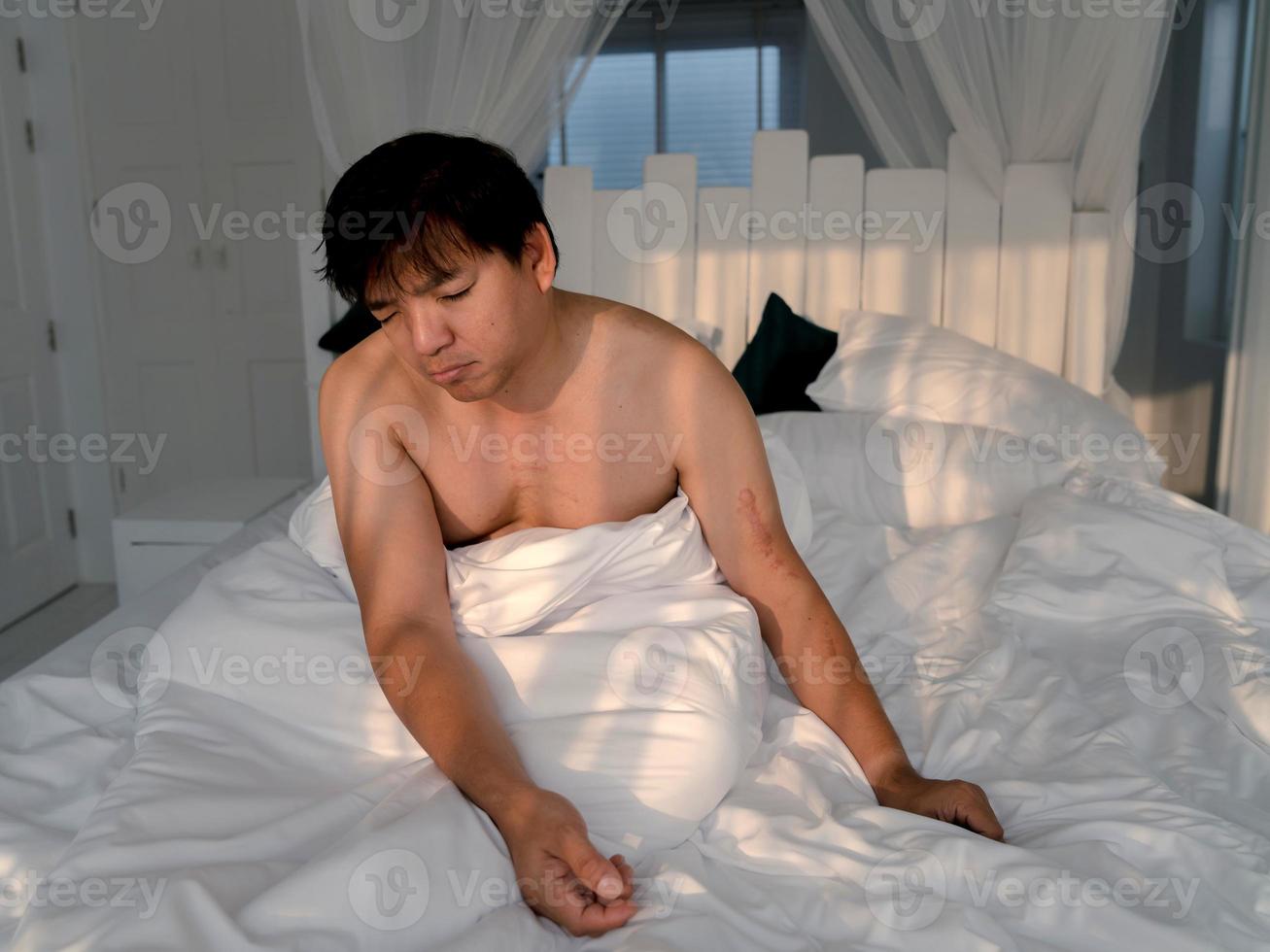 fauler mann sitzt schlafend im bett foto