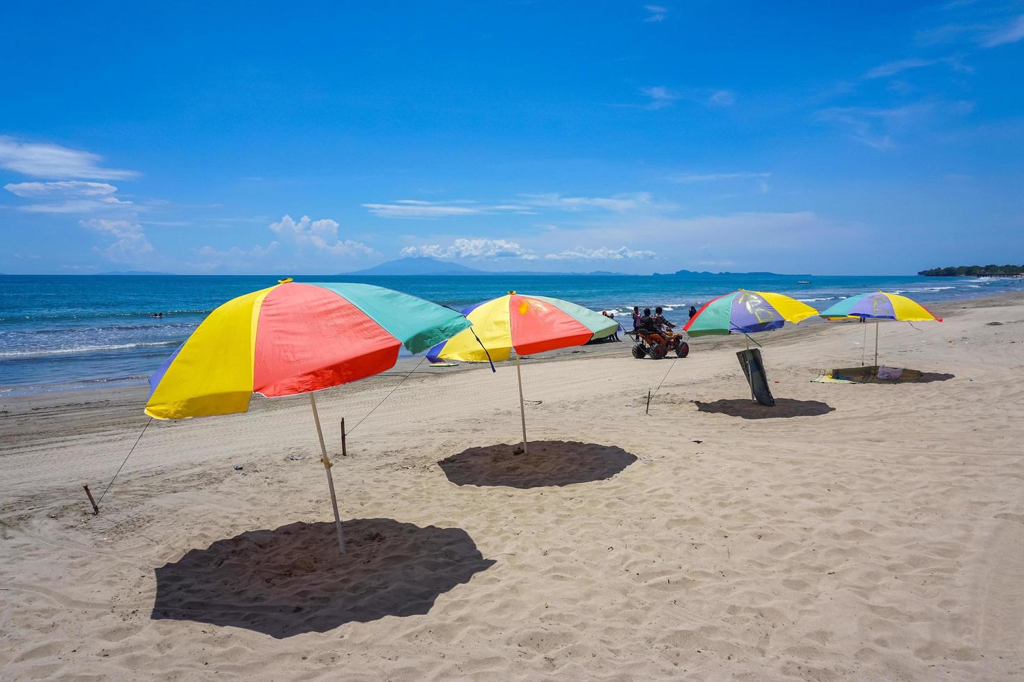 bunter Regenschirm am Sandstrand unter blauem Himmel. sommerferien reisen. tropische urlaubsreisen. kostenloses Foto