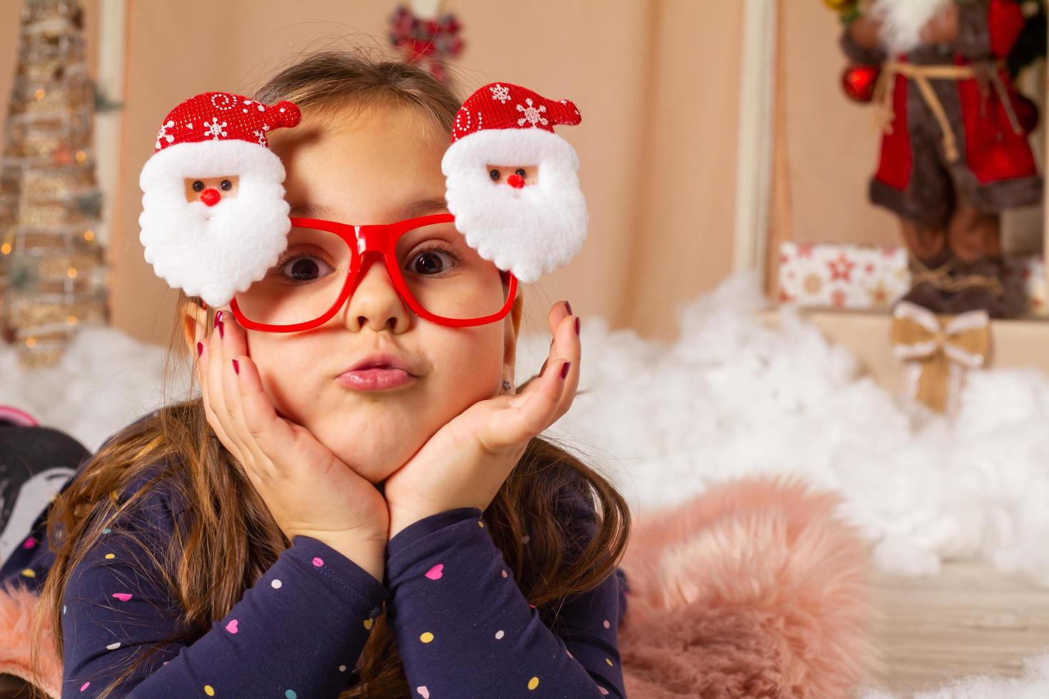 kleines Mädchen mit Weihnachtsbrille und Grimassen foto
