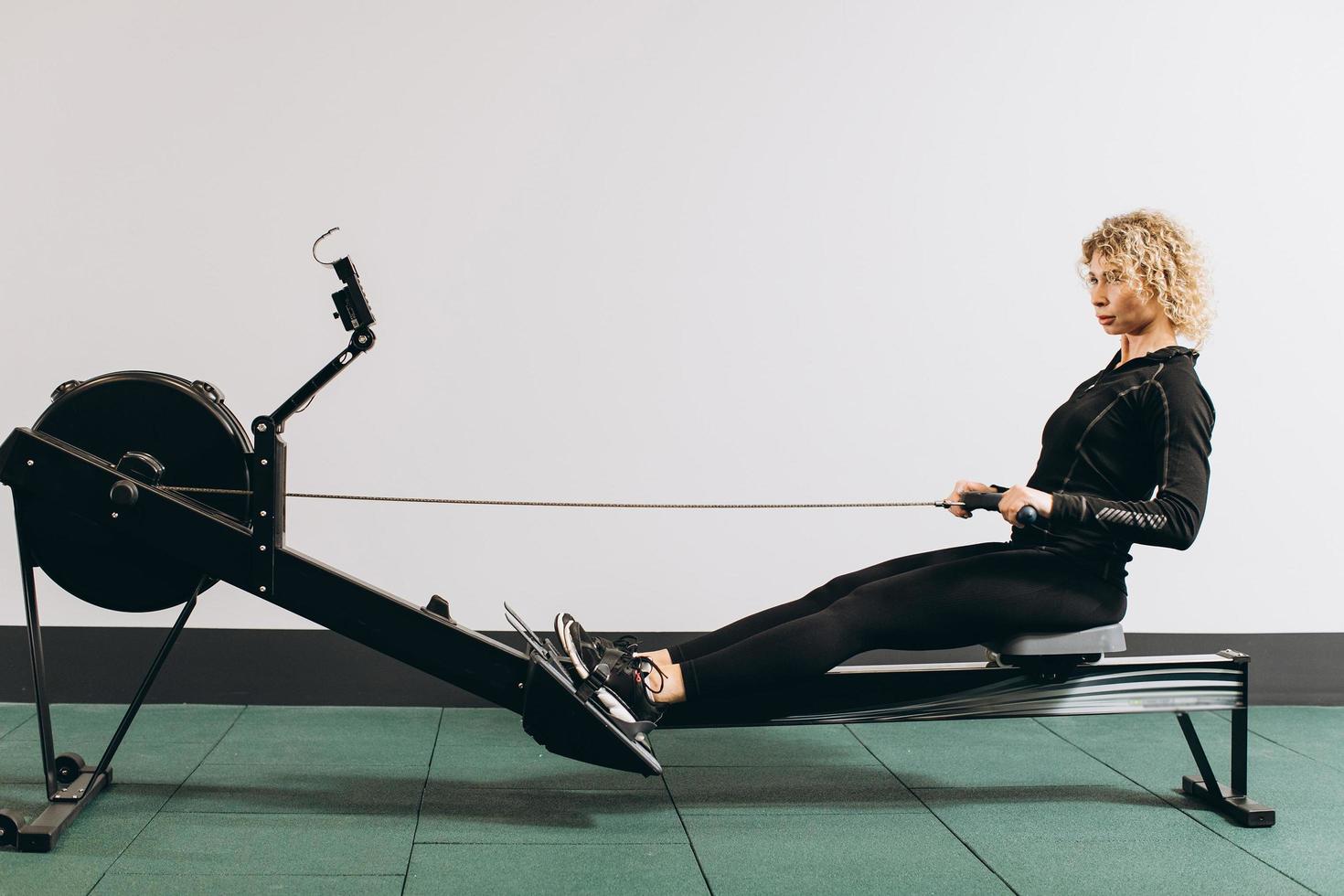 Frau, die auf Rudergerät trainiert, Teil des Zirkeltrainings Aufwärm-Cardio-Session foto