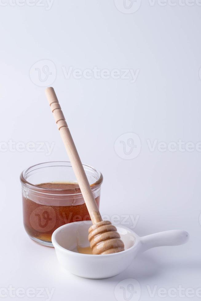 Honig in einem klaren Glas und Honigschöpflöffel foto