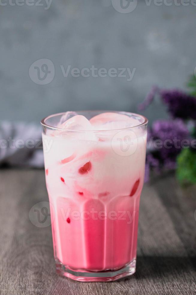 kaltes rosa milchkaltes getränk im klaren glas auf grauem hintergrund. thailändische Milch foto