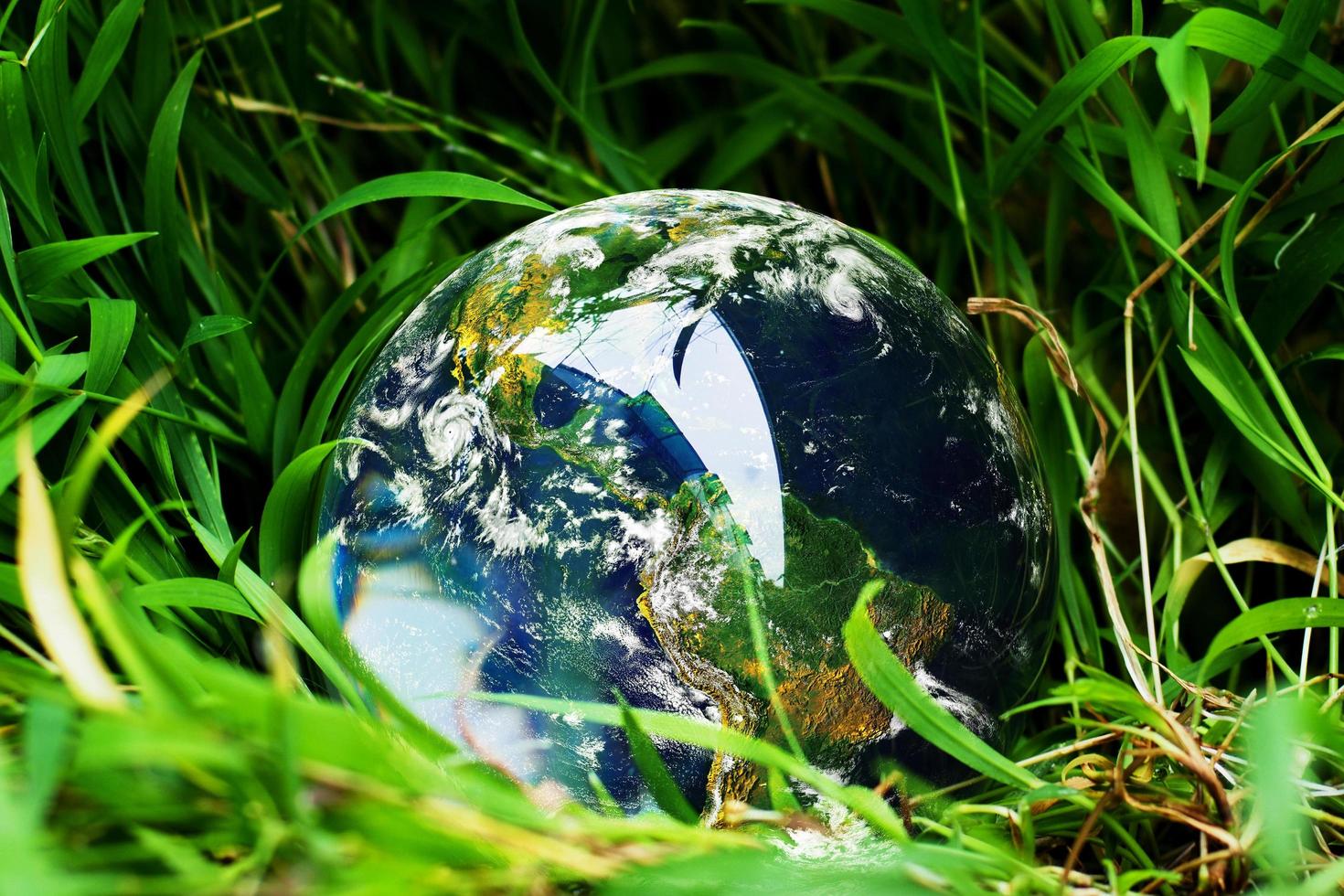 die Kristallkugel mit der Welt auf dem Rasen. Konzept der Welt und der Natur foto