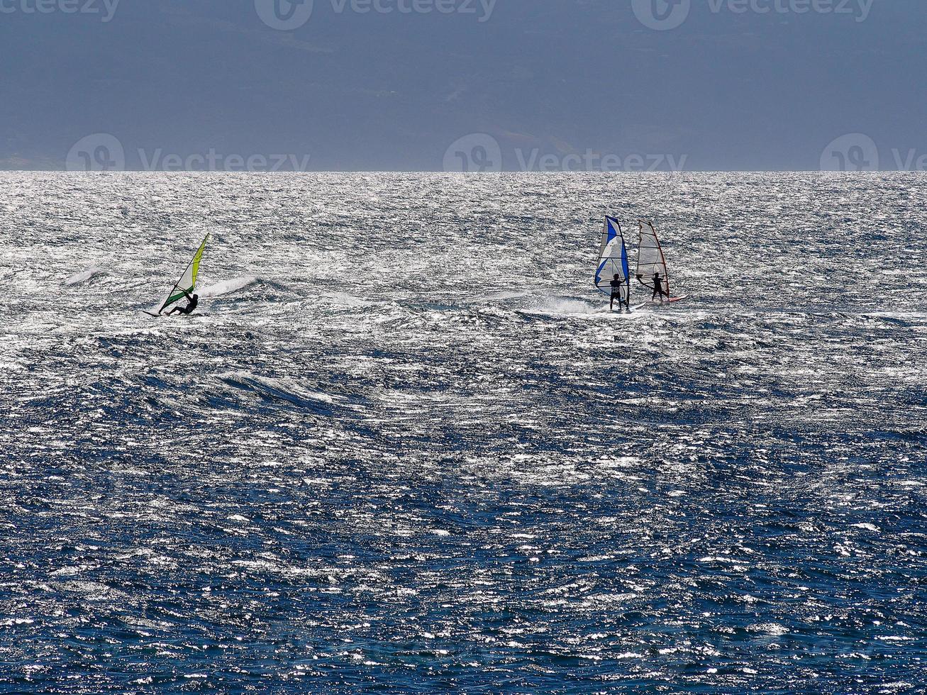 blaues wasser drei windsurfer strahlende sonne foto