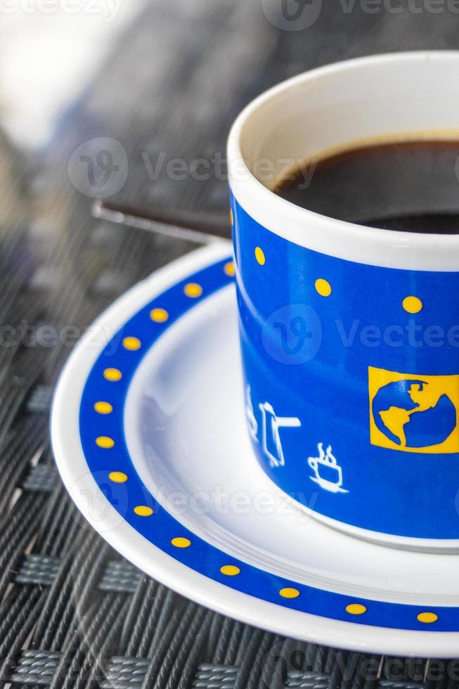 schwarzer kaffee in einer blauen tasse mit weltkugeln, thailand. foto