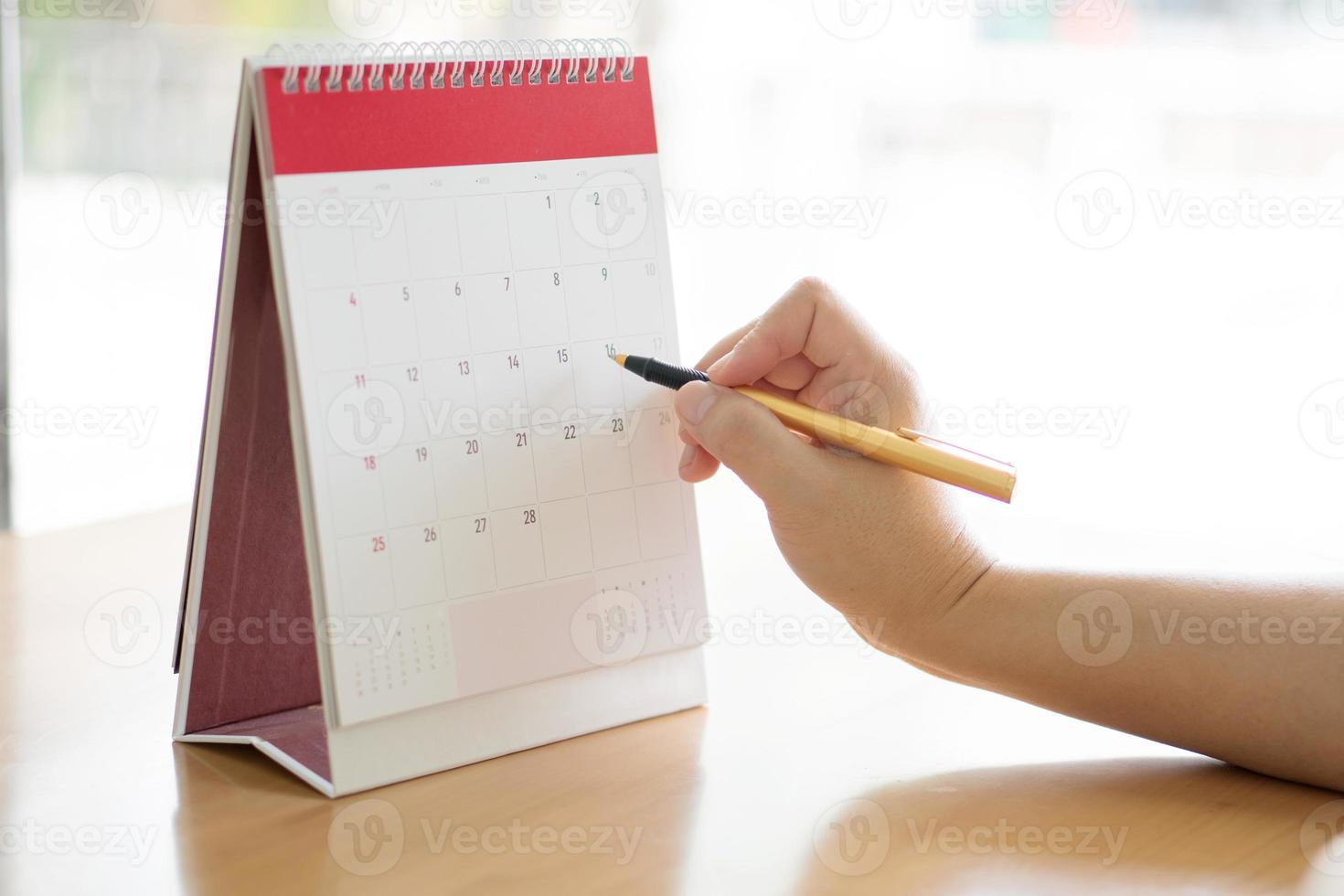 Frauenhand, die Kalender trägt und mit dem Stift darauf zeigt foto