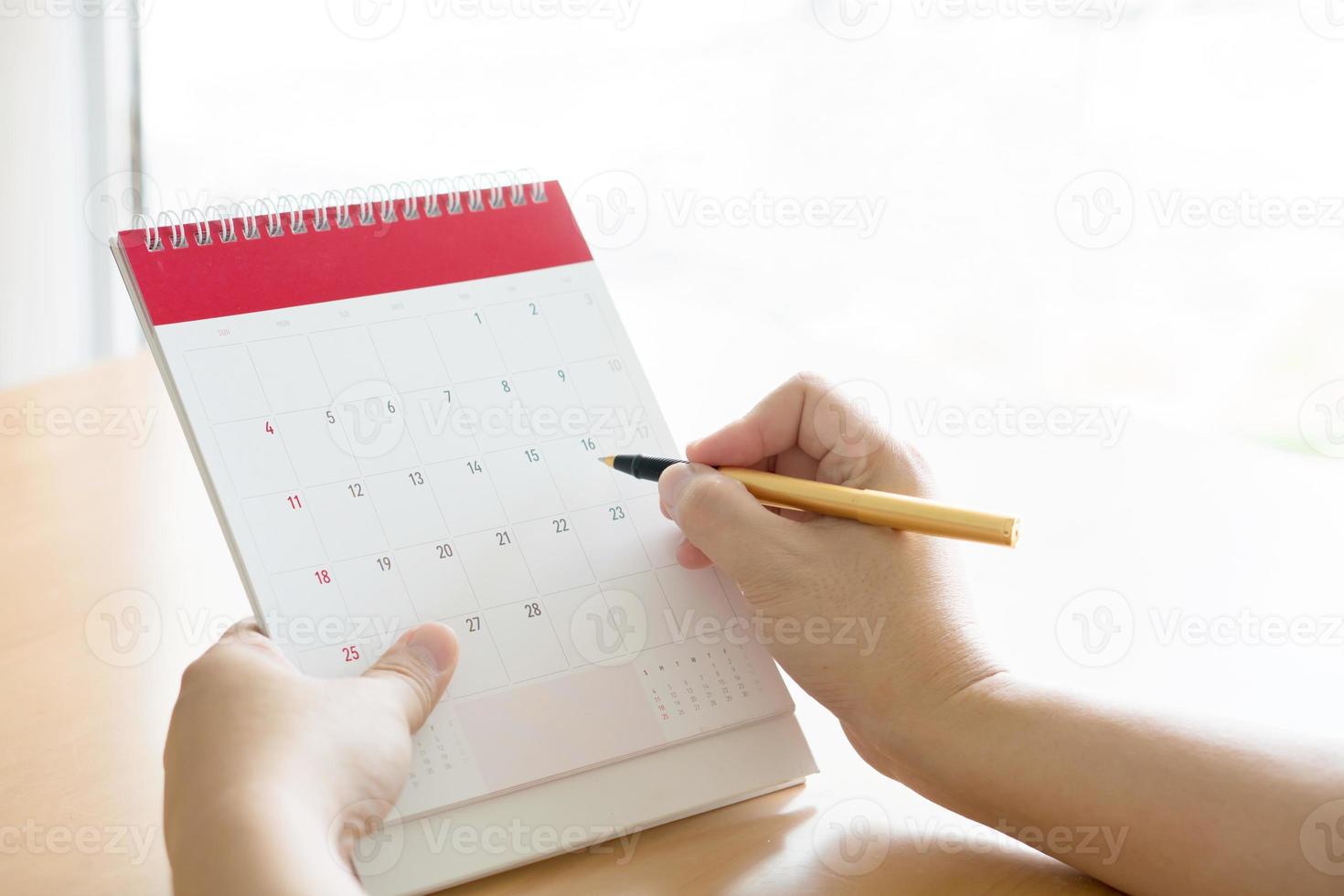 Frauenhand, die Kalender trägt und mit dem Stift darauf zeigt foto