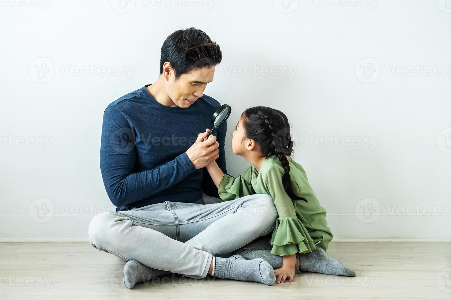 glücklicher vater, der mit einer tochter zu hause lupe spielt foto