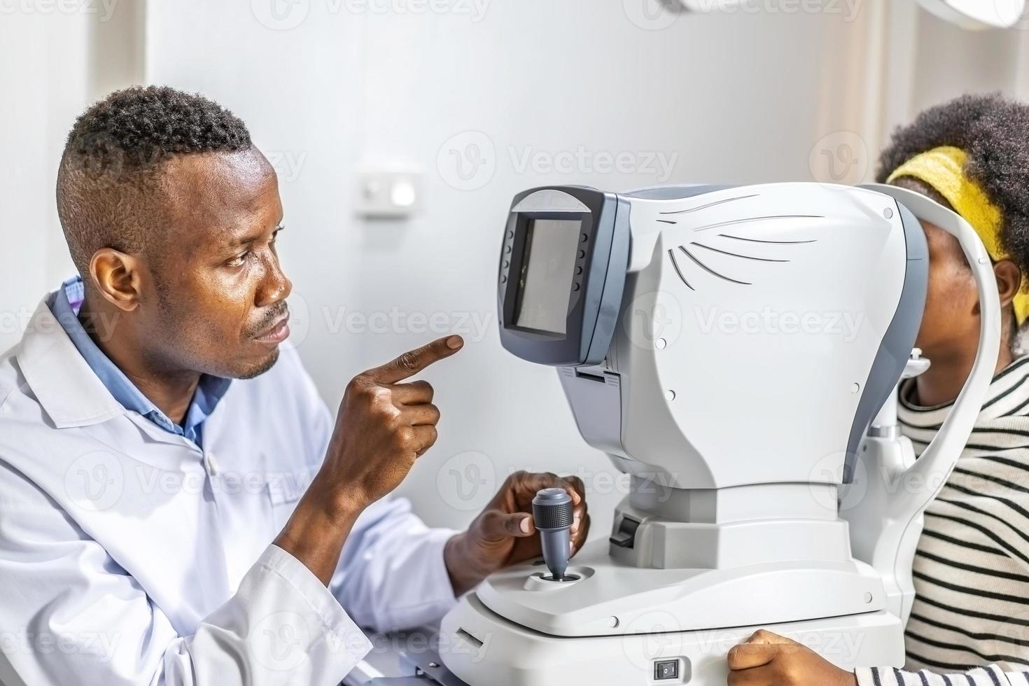 Der Augenarzt des männlichen Arztes überprüft das Sehvermögen eines schwarzafrikanisch-amerikanischen Teenager-Mädchens in einer modernen Klinik. Arzt und Patient in der Augenklinik. foto