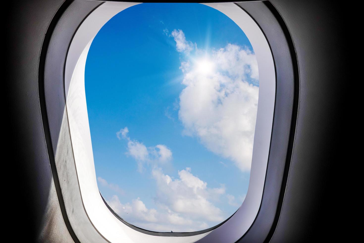 blauer himmel und sonnenblick mit weißen wolken, die von innen aus einem flugzeugfenster betrachtet werden, konzept von reise und lufttransport foto