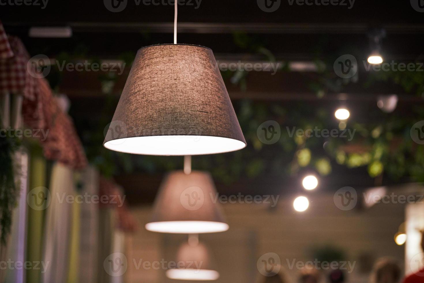 Pendelleuchten über Tischen im Restaurant. Modernes, niedrig gedimmtes, warmes Licht mit Lampenschirmen foto