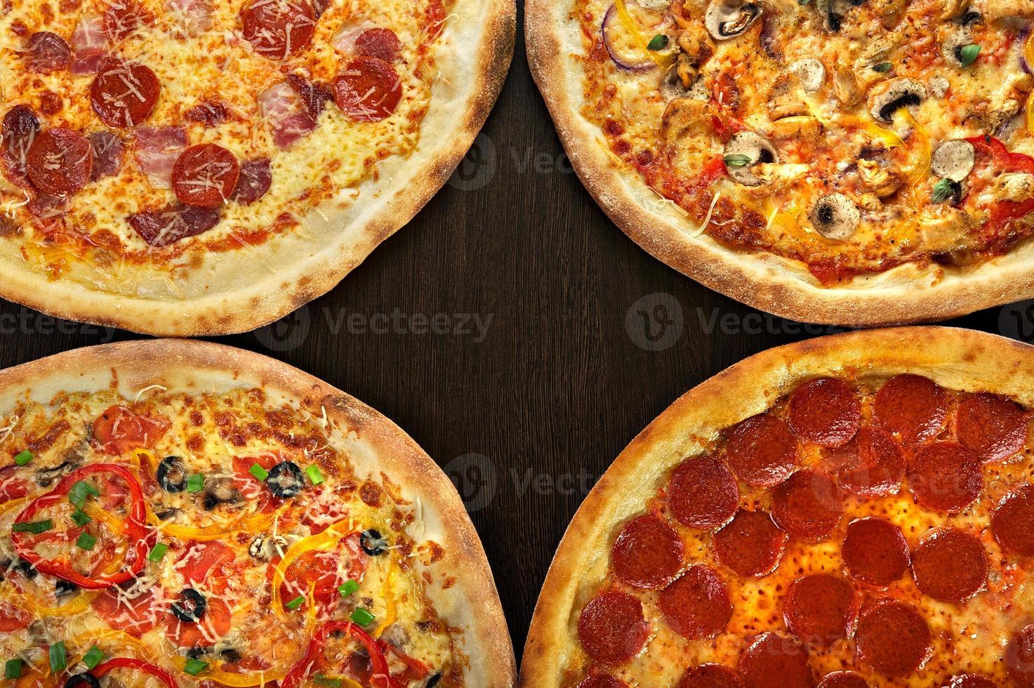 vier Pizza auf einem dunklen hölzernen Hintergrund foto