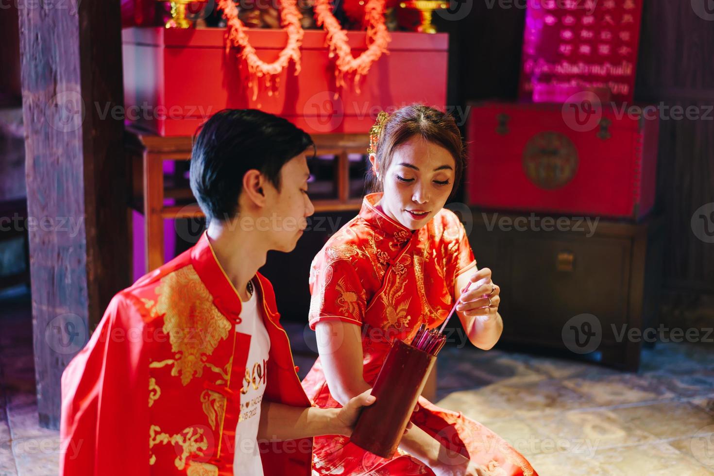 glückliches junges asiatisches paar in chinesischen traditionellen kleidern, die im tempel beten foto