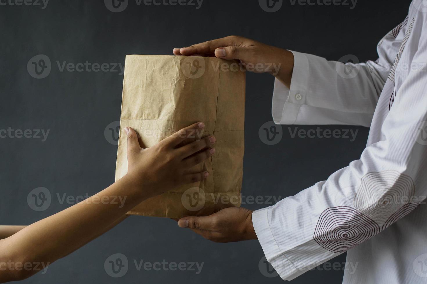 Seitenansicht muslimischer Hände, die Reis-Almosenbeutel teilen, isoliert auf schwarzem Hintergrund. foto