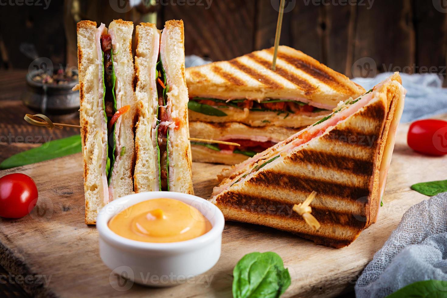 Club-Sandwich mit Schinken, Tomate, Käse und Spinat. gegrillte panini foto