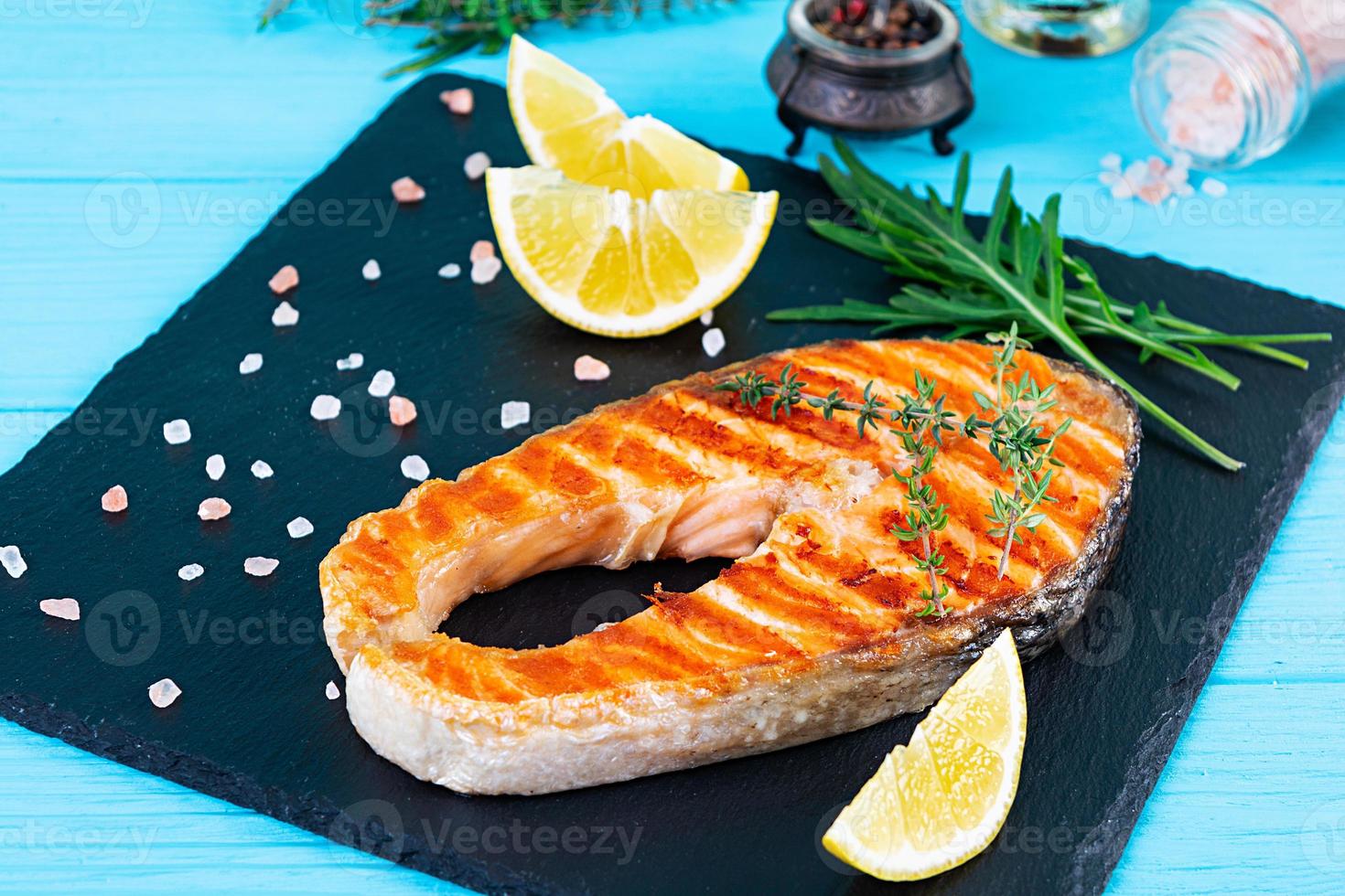 gegrillter Lachsfisch auf Steinplatte. gesalzener atlantischer lachs, gebraten auf dem grill mit zitrone foto