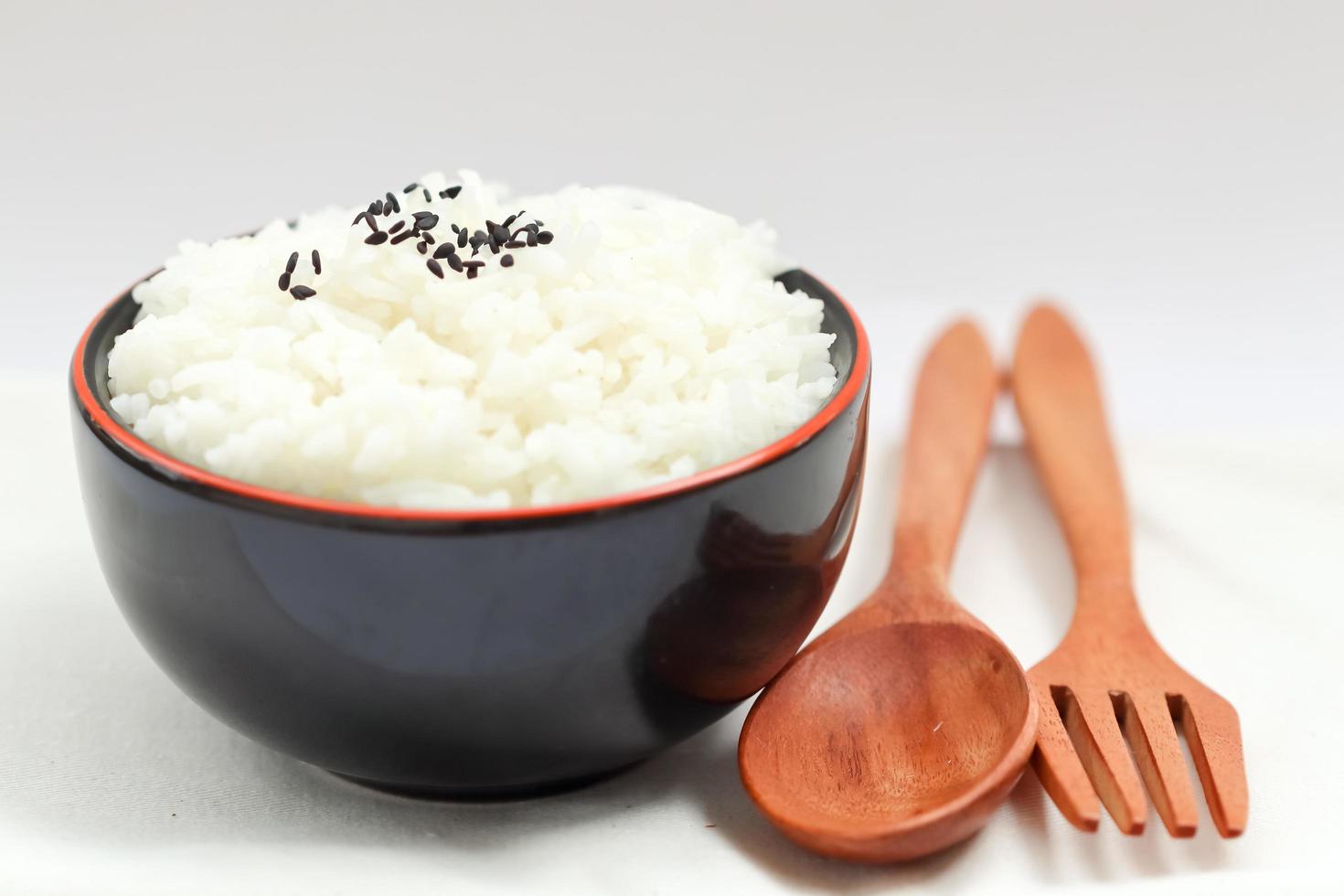 Reis auf der hinteren Schüssel, Holzlöffel und Gabel mit weißem Hintergrund. foto