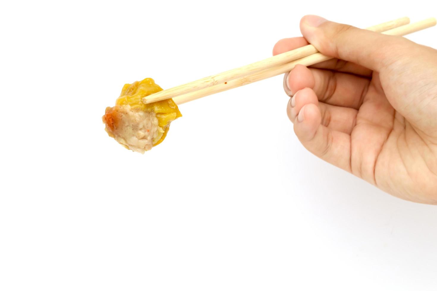 Hand, chinesischer Bachknödel und Essstäbchen mit weißem Hintergrund. foto