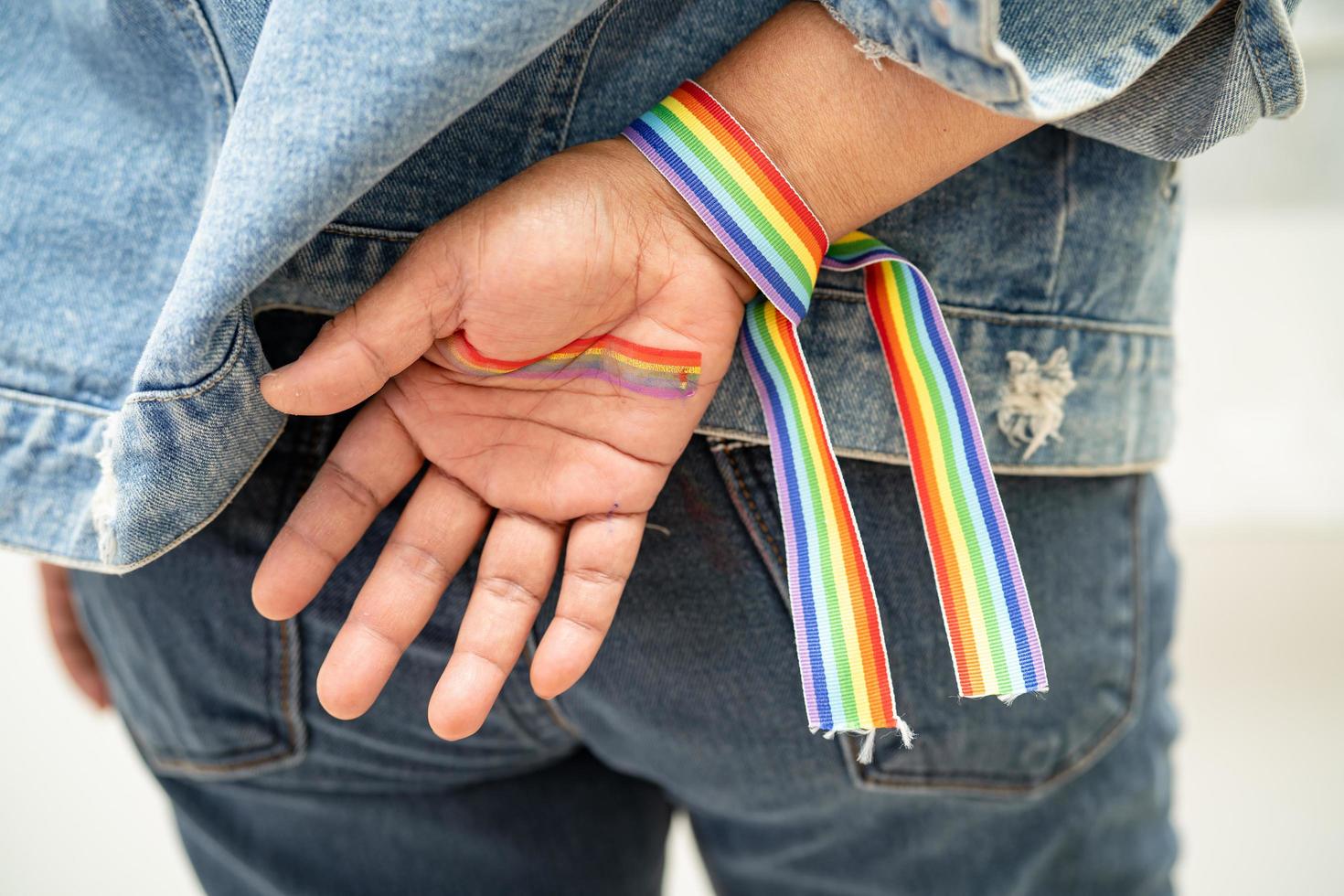 asiatische dame mit regenbogenflaggenarmbändern, symbol des lgbt-stolzmonats, feiert jährlich im juni die sozialarbeit von schwulen, lesbischen, bisexuellen, transgendern und menschenrechten. foto