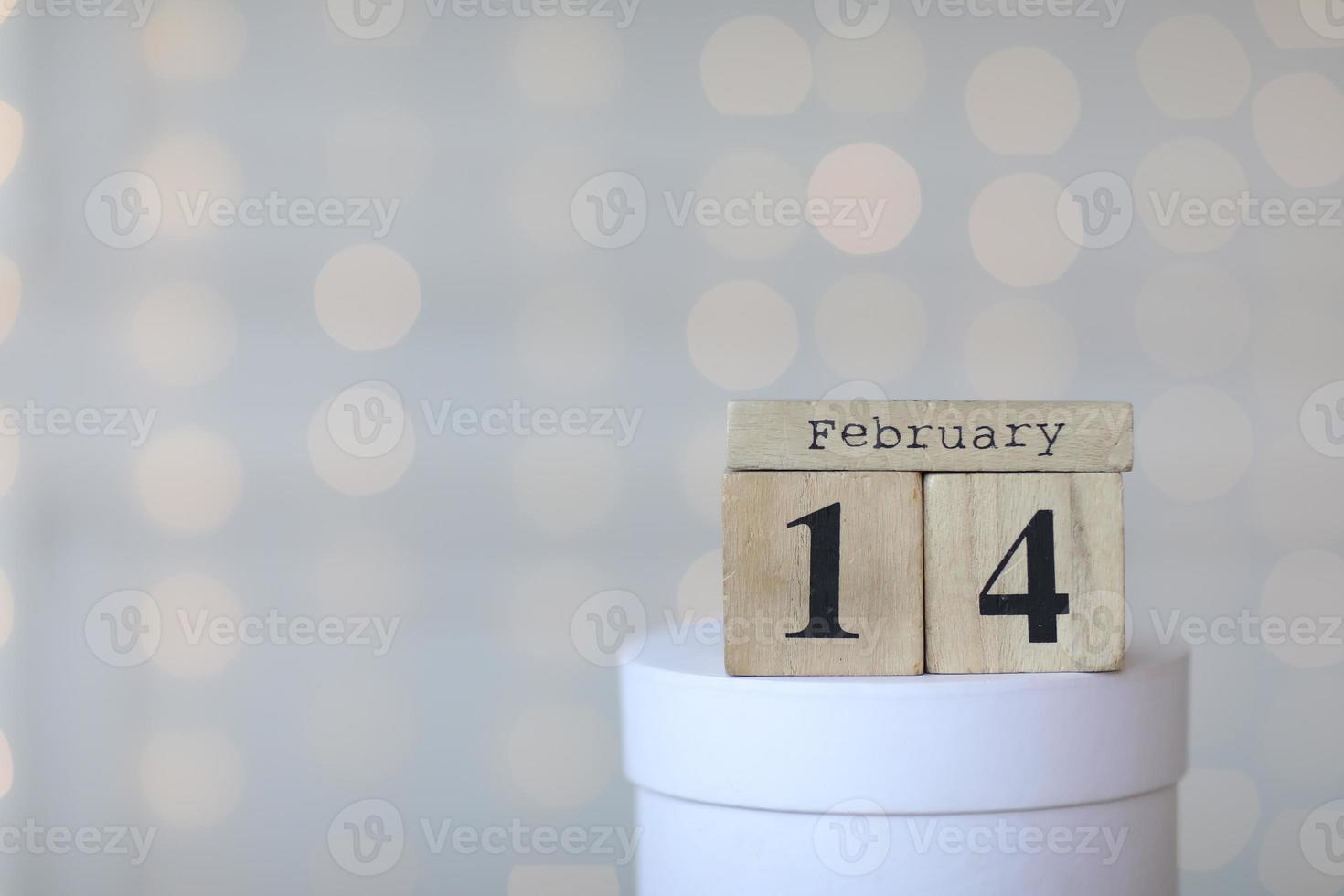 Valentinstag-Konzept. datum 14. februar auf hölzernem rotem würfelkalender auf einer weißen geschenkbox. Bokeh goldener und weißer Hintergrund. foto