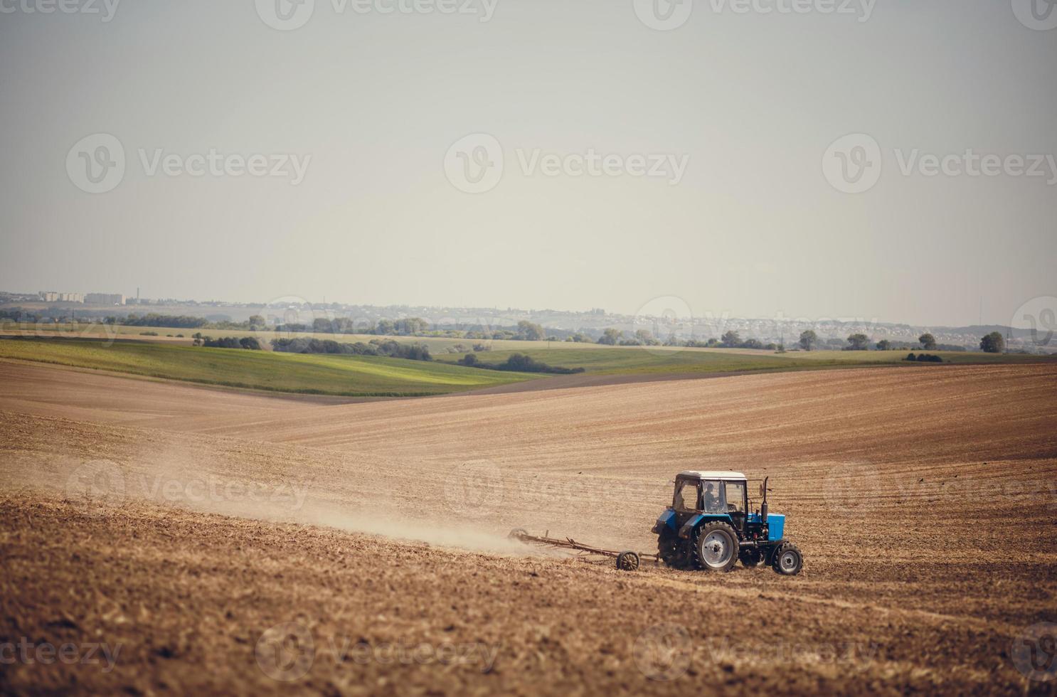 landwirtschaft verwenden traktor, der landfeld pflügt. bebautes Feld. agronomie, landwirtschaft, zucht. traktor, der auf dem bauernhof arbeitet, moderner landwirtschaftlicher transport, landwirt, der auf dem feld arbeitet foto